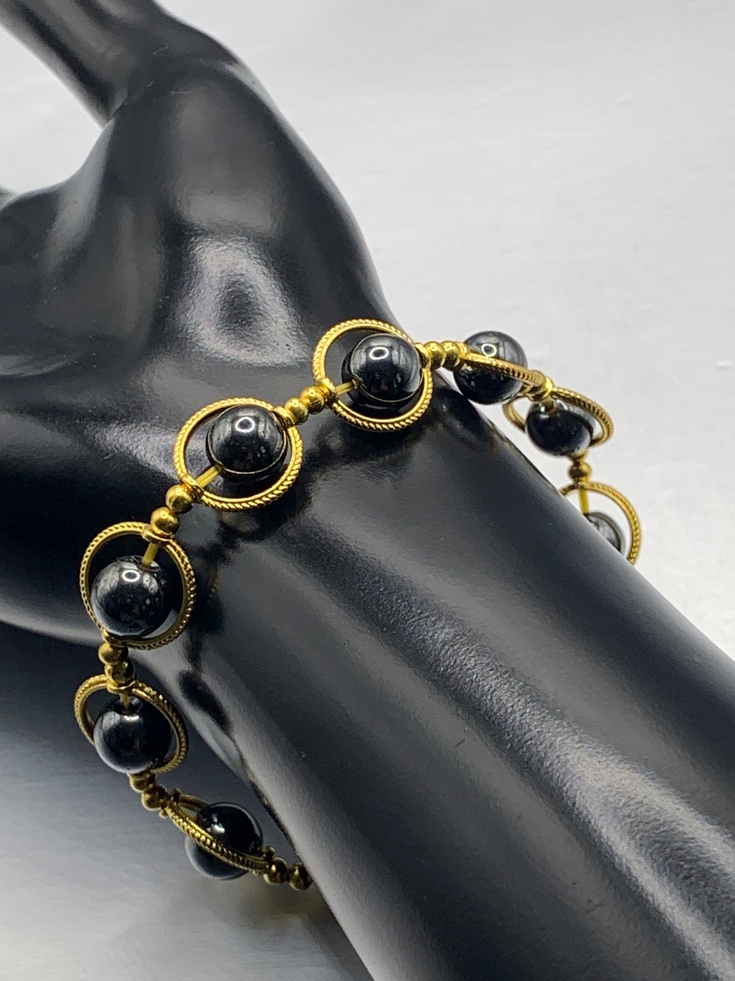 Hematite semi precious stone/crystal elastic beaded bracelet with gold colored rings