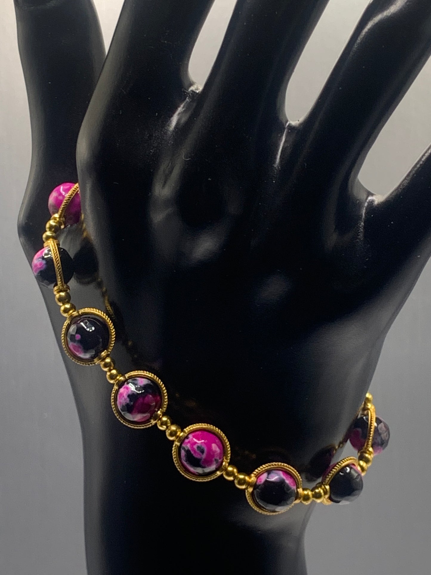 Bracelet with pink and black orca agate gemstones on a black mannequin hand