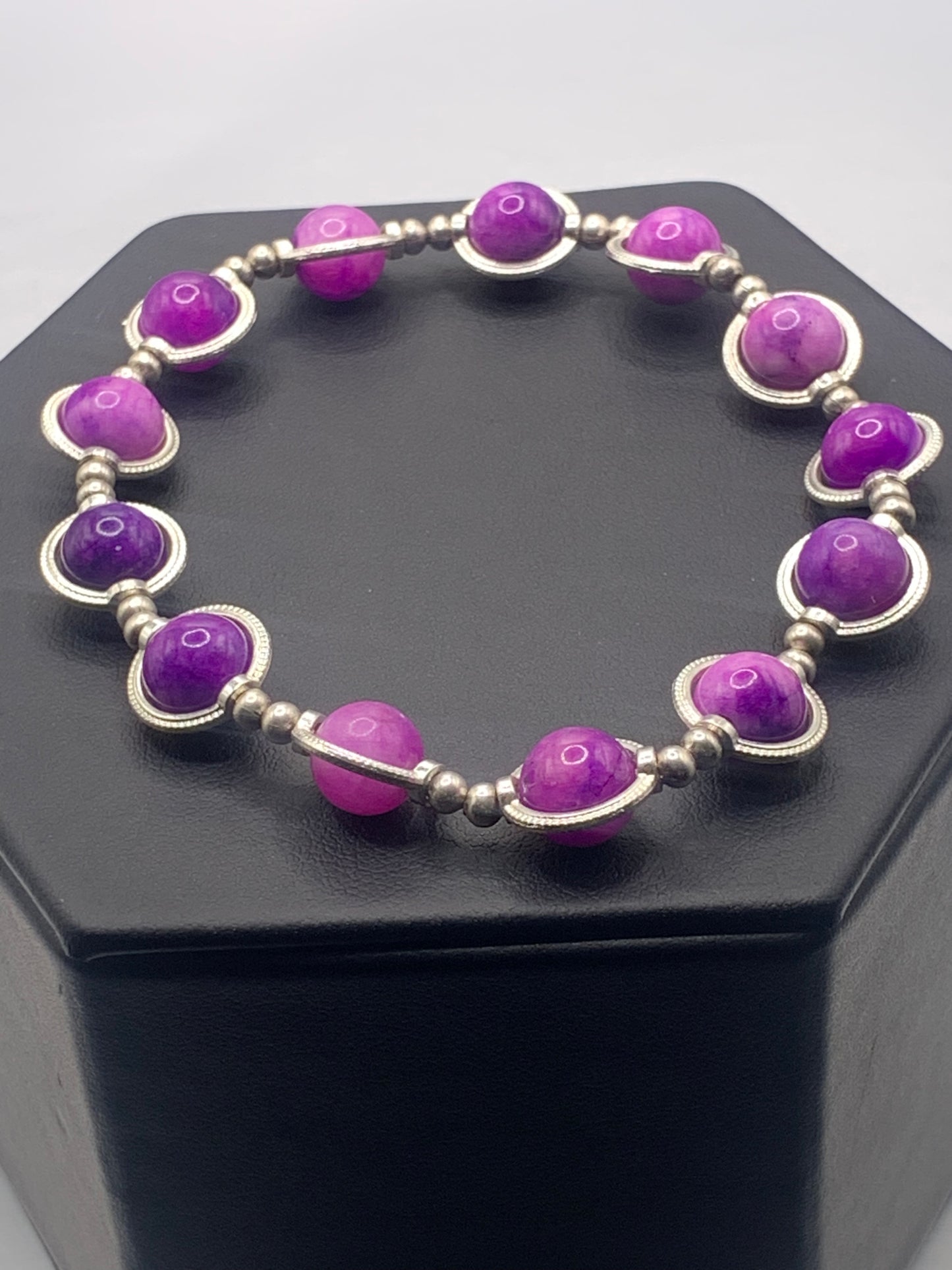 Bracelet with purple charoite beads and silver accents on a black stand