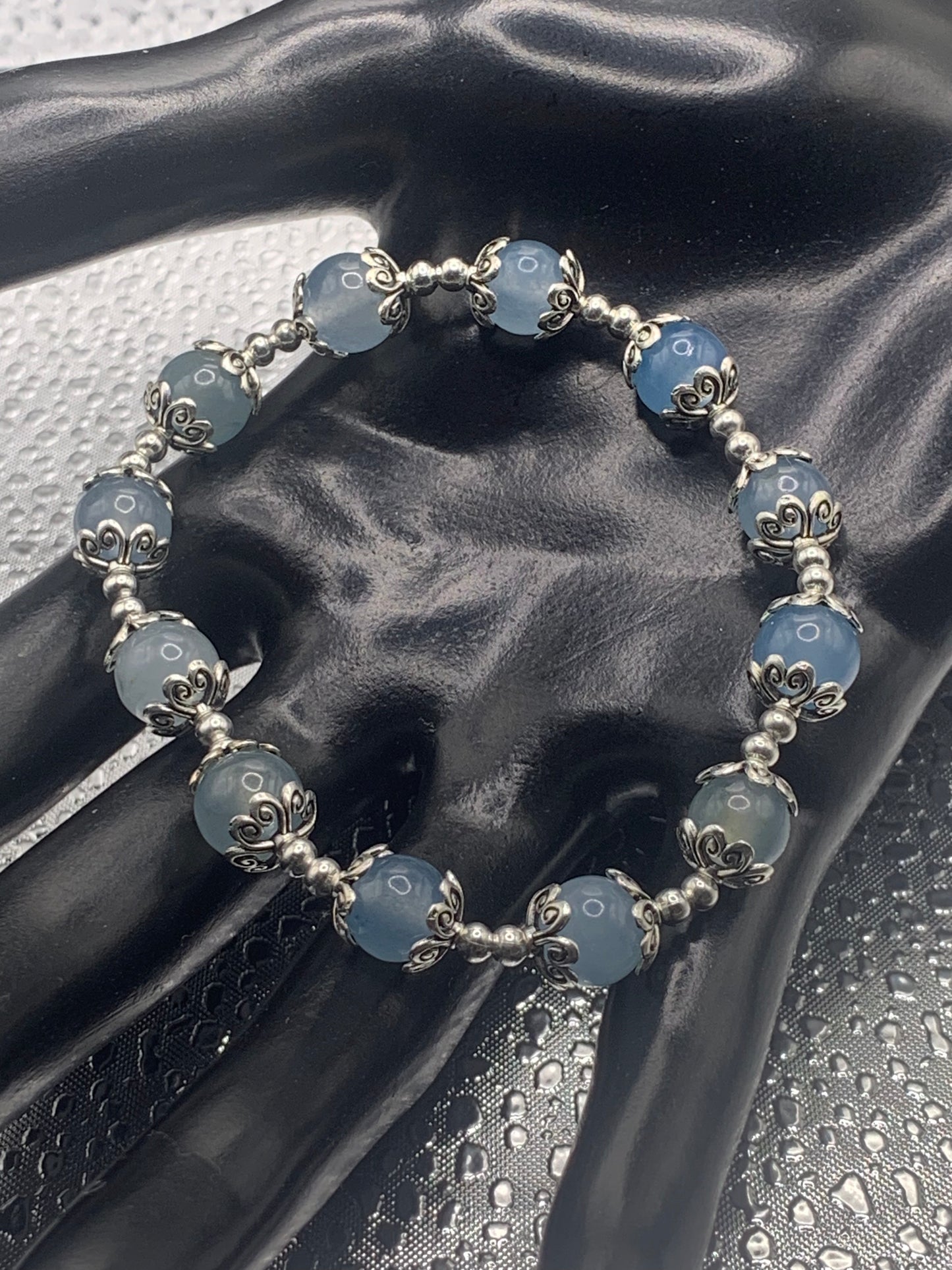 This bracelet contains blue agate beads that are surrounded by bead caps and spacer beads
