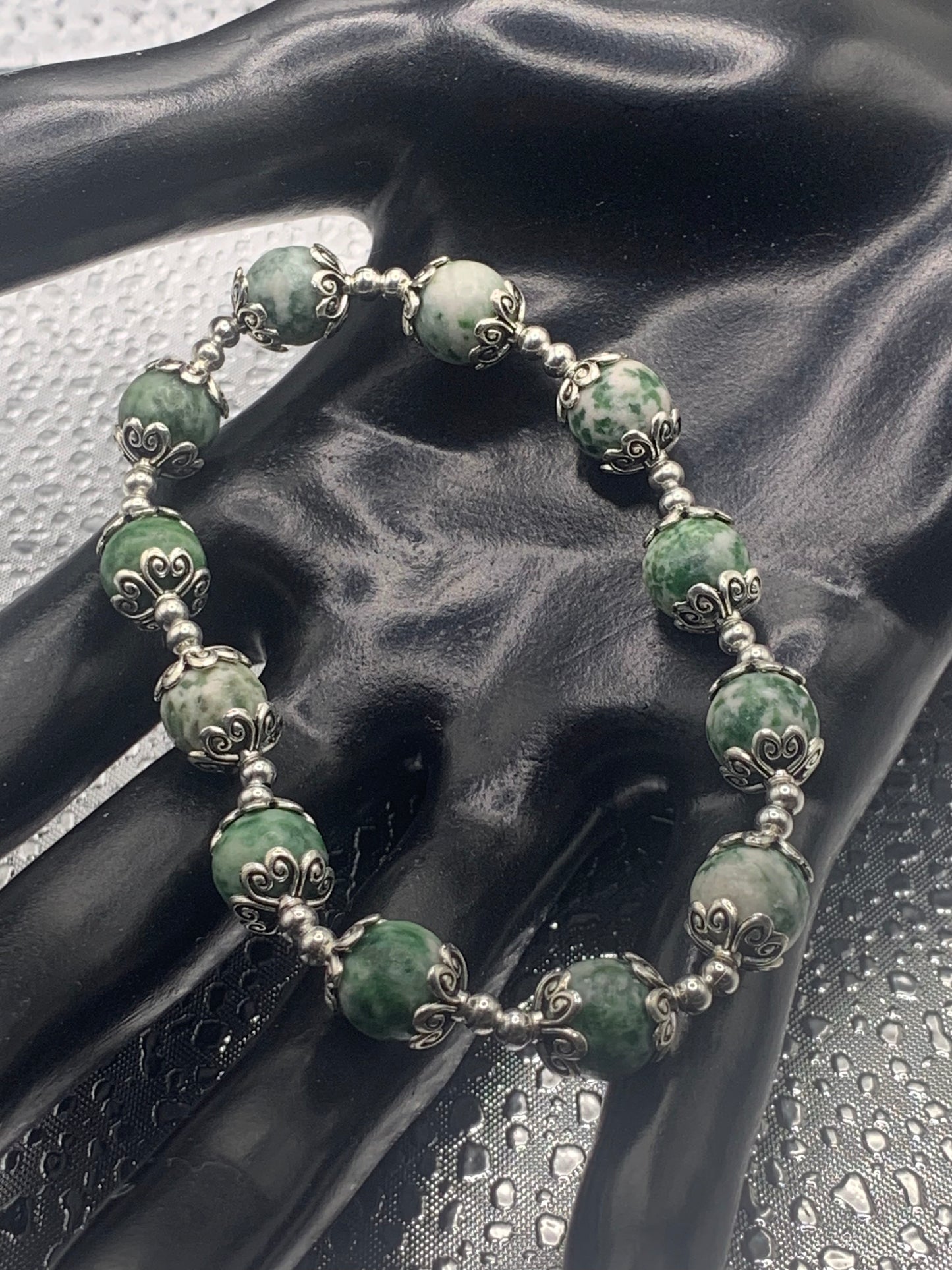 This bracelet contains green dot jasper beads that are surrounded by bead caps and spacer beads