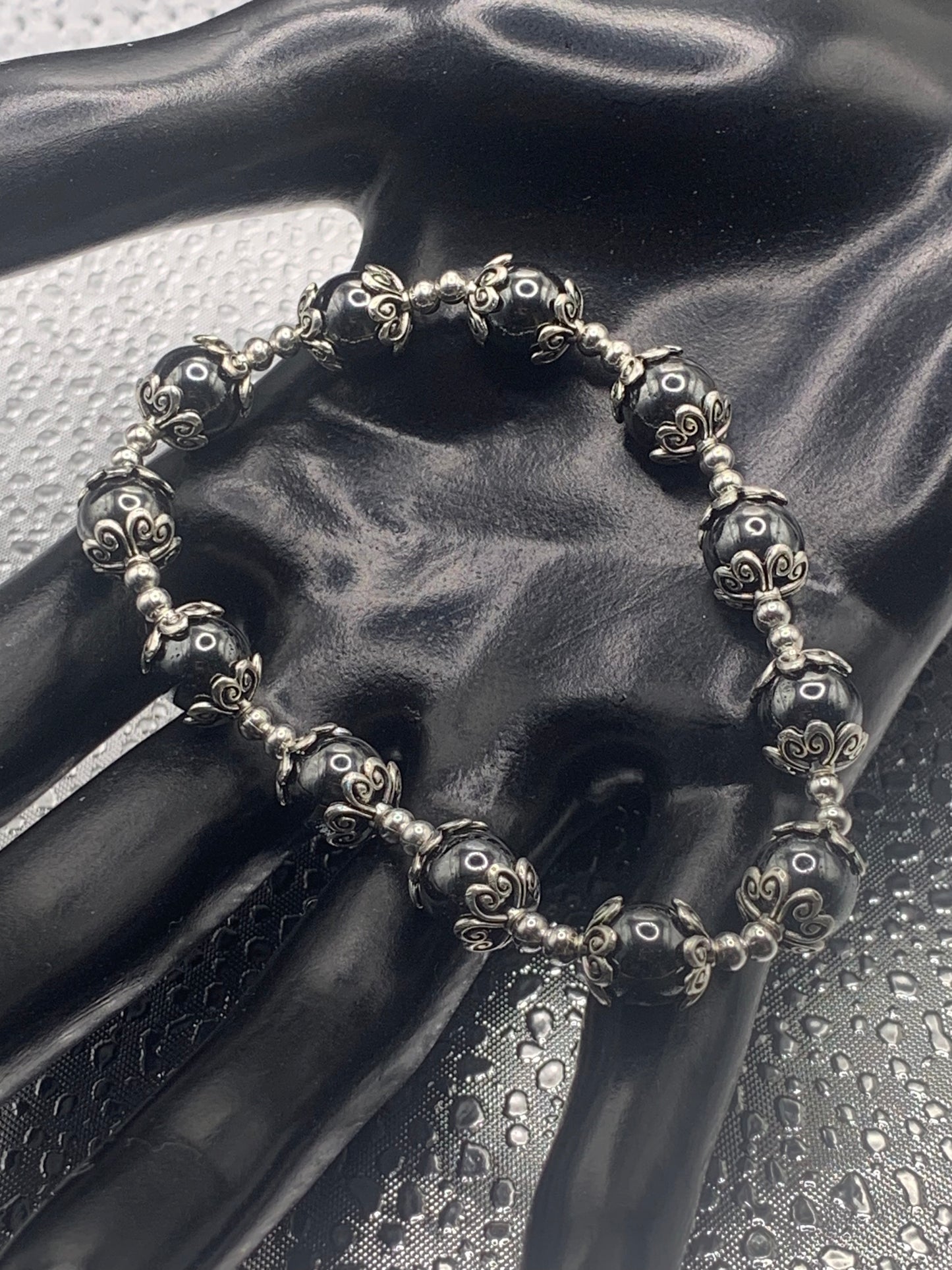 This bracelet contains hematite beads that are surrounded by bead caps and spacer beads