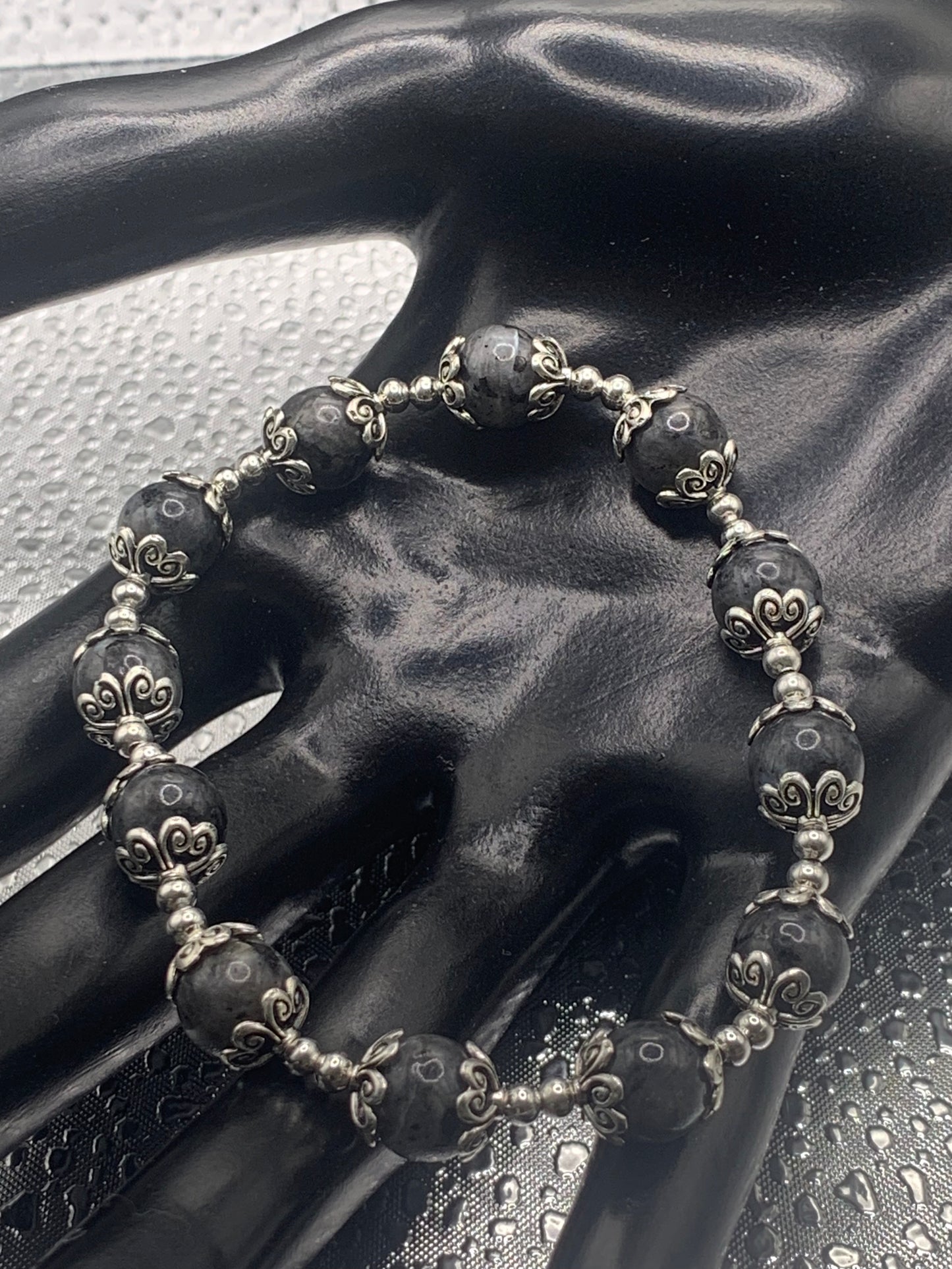 This bracelet contains larvikite beads that are surrounded by bead caps and spacer beads.