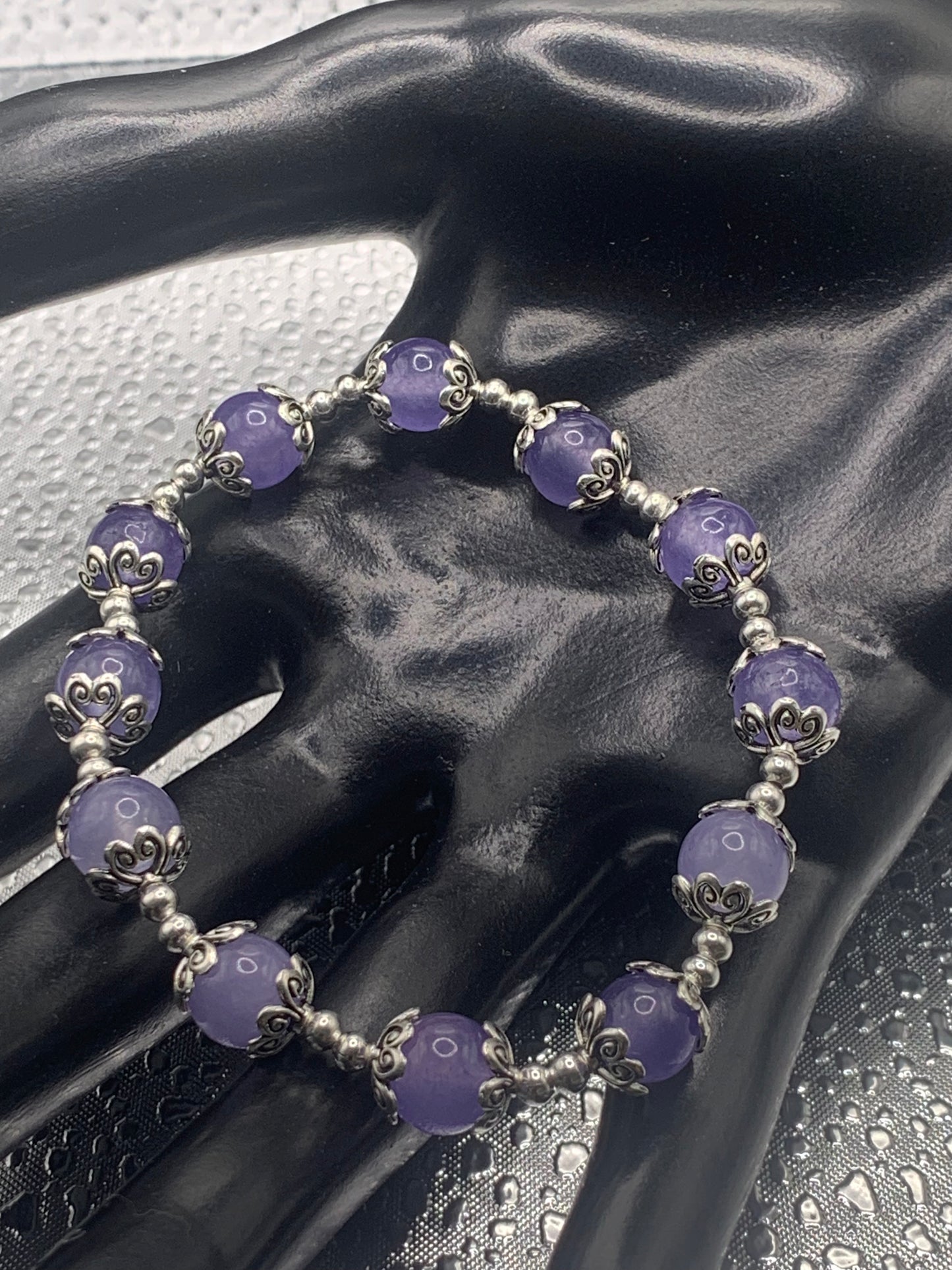 This bracelet contains purple agate beads that are surrounded by bead caps and spacer beads