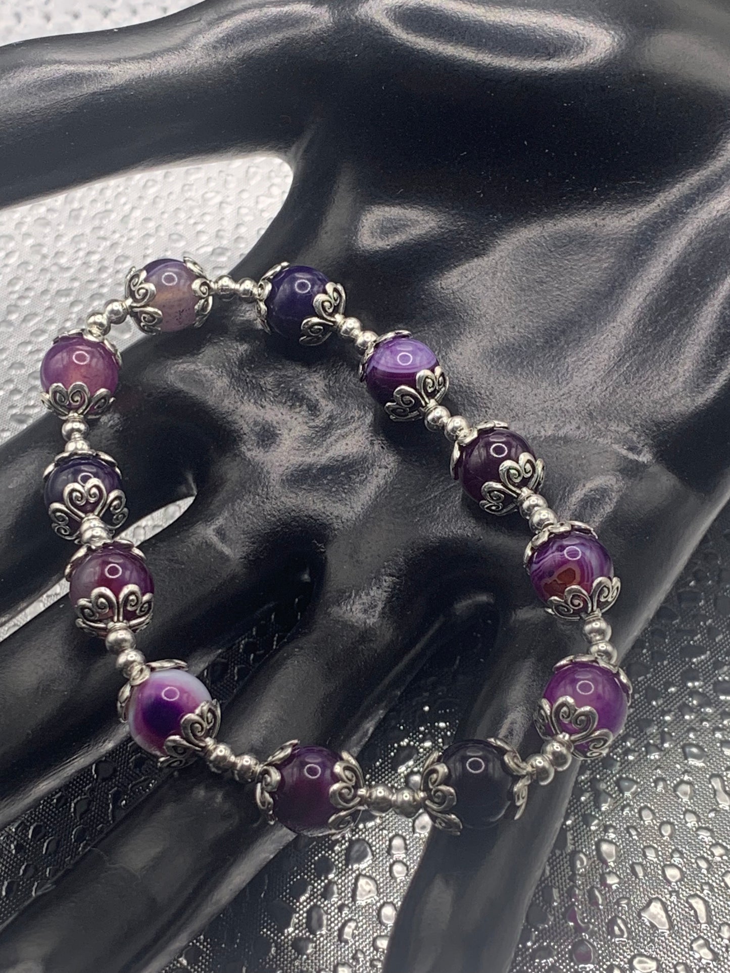 This bracelet contains purple lace agate beads that are surrounded by bead caps and spacer beads