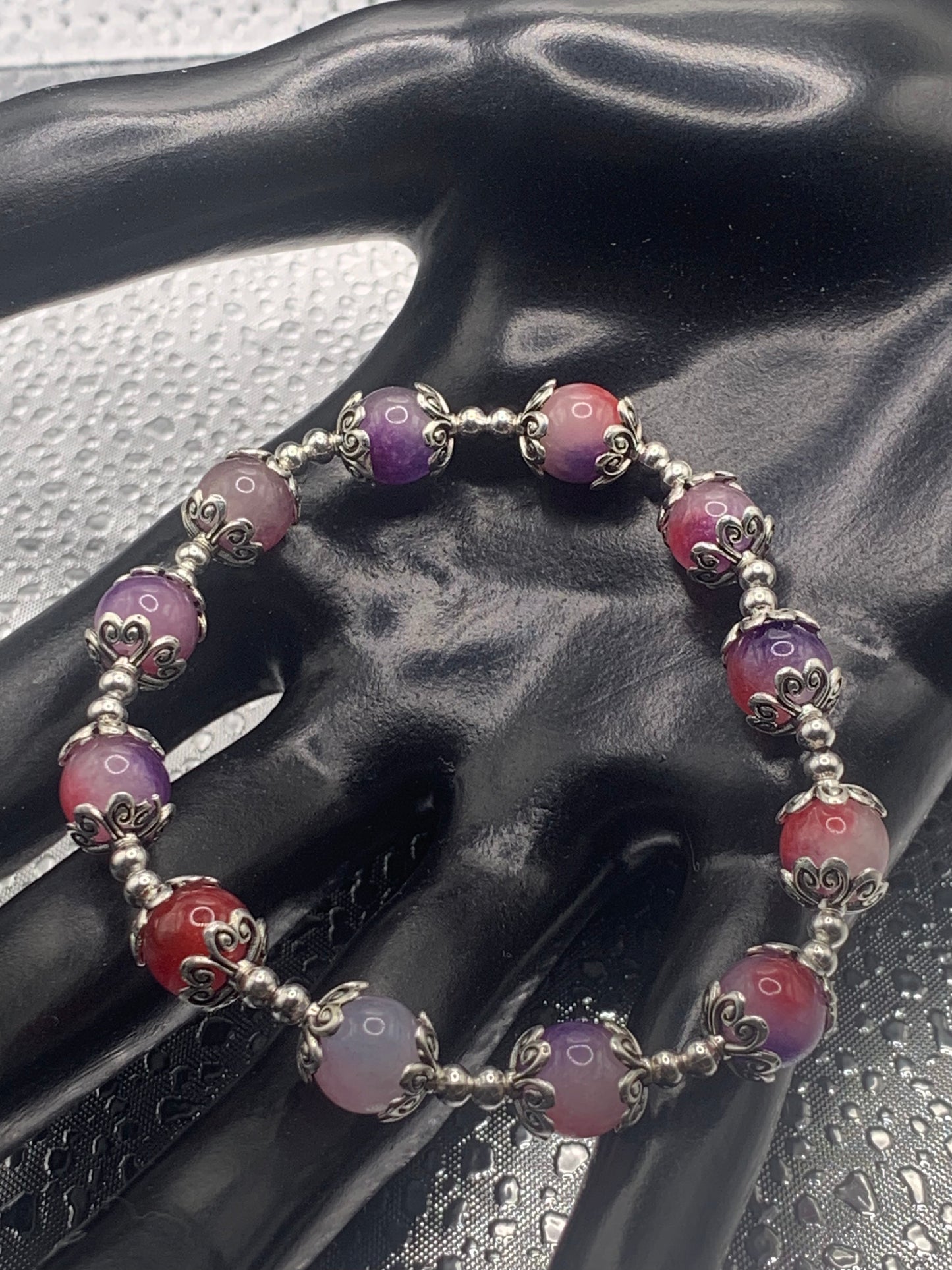 This bracelet contains purple pink agate beads that are surrounded by bead caps and spacer beads