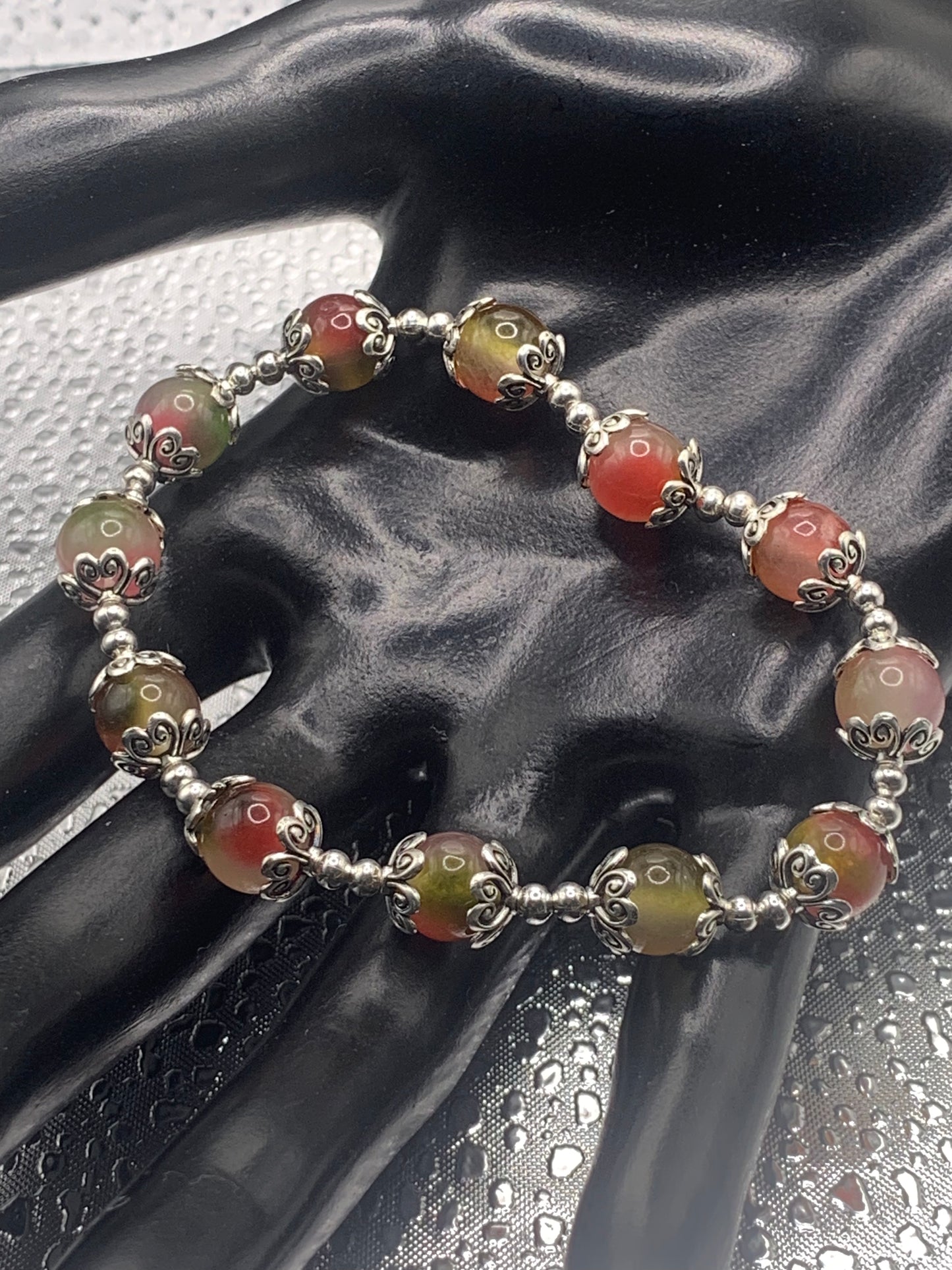 This bracelet contains watermelon agate beads that are surrounded by bead caps and spacer beads