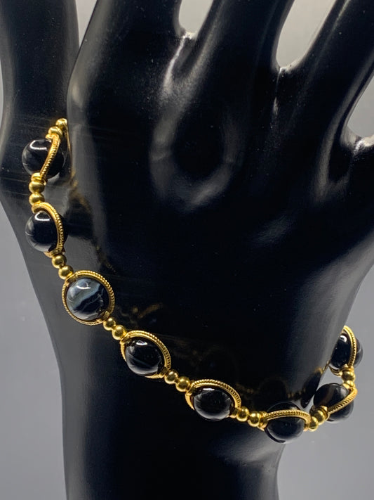 Black lace agate beaded bracelet with gold accents on a black mannequin hand