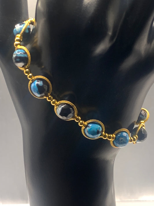 Bracelet with blue orca agate beads and gold accents on a black mannequin