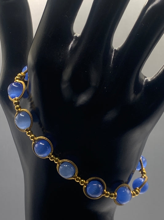 Bracelet with blue cats eye beads and gold accents on a black mannequin hand