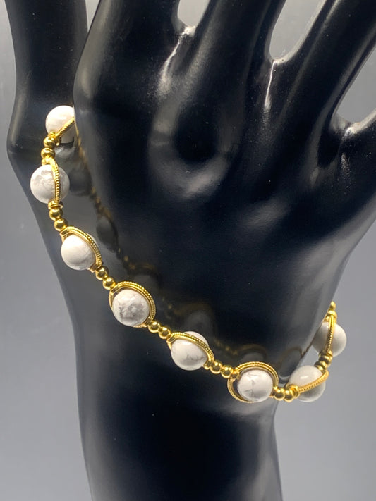 White howlite bead bracelet with gold rings on a black mannequin hand