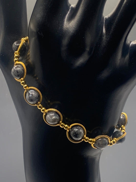 Bracelet with gold accents and larvikite beads on a black mannequin.