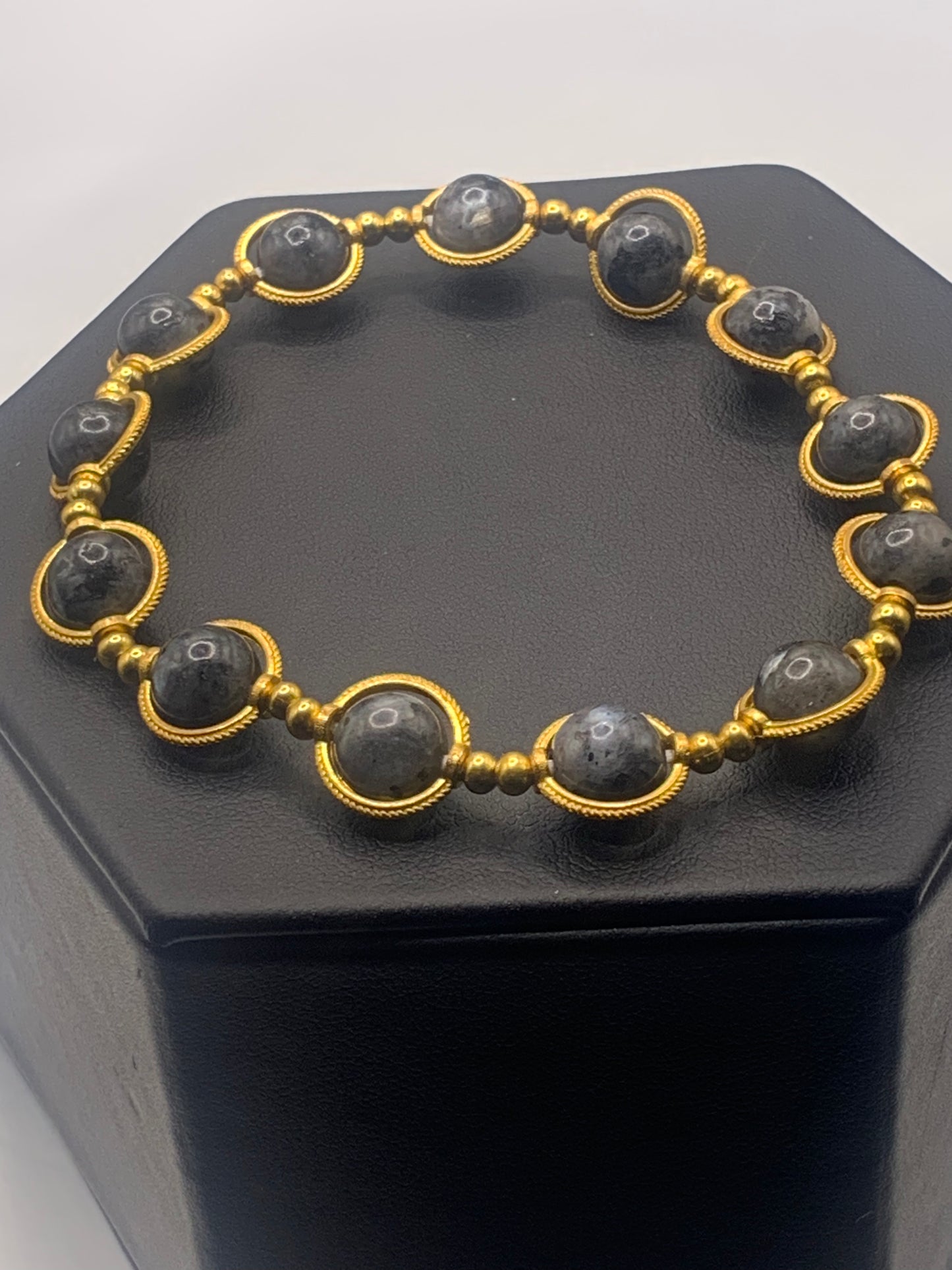 Bracelet with larvikite beads and gold accents on a black stand