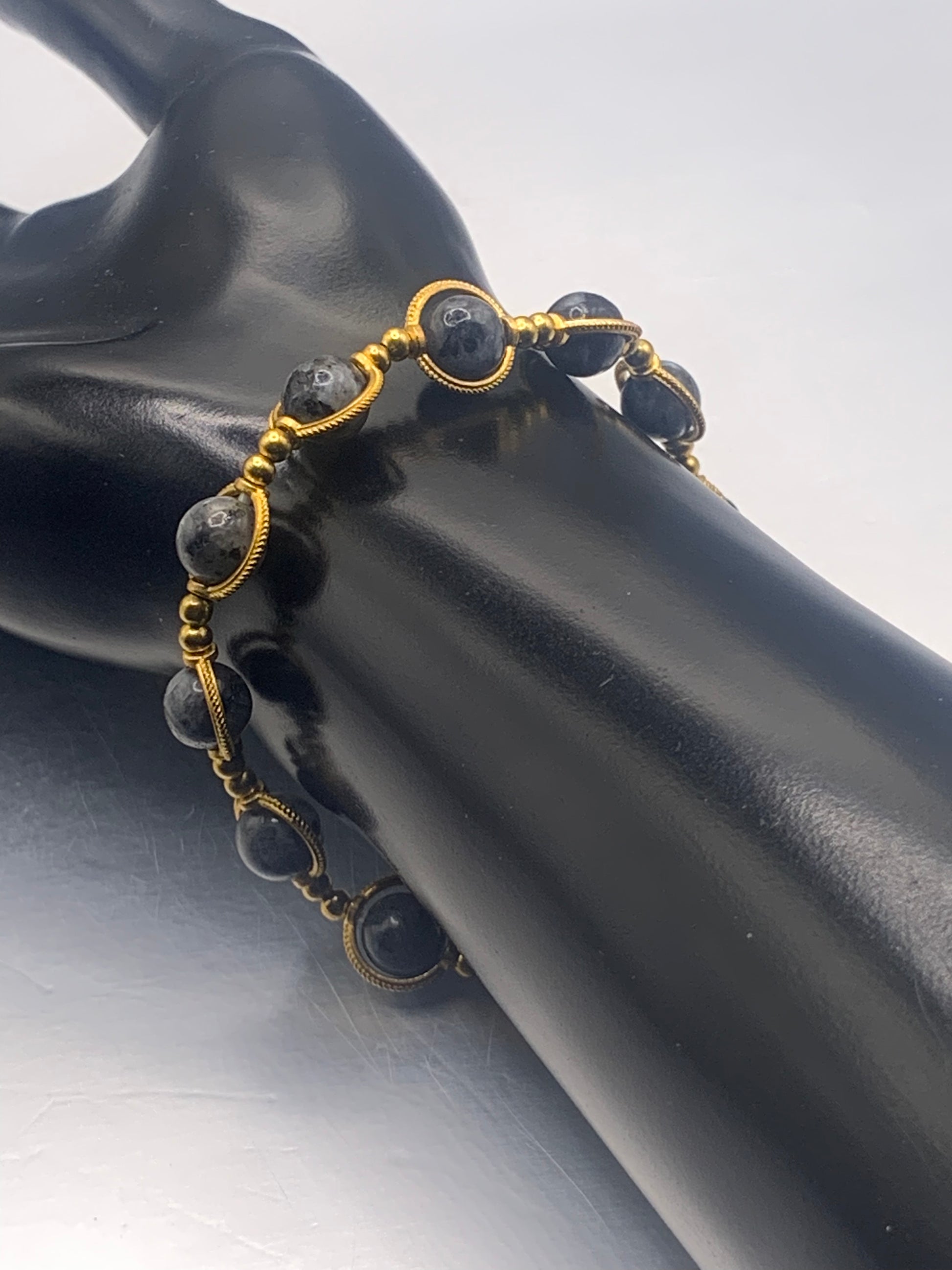 Larvikite beaded bracelet with gold accents on a black mannequin arm against a neutral background