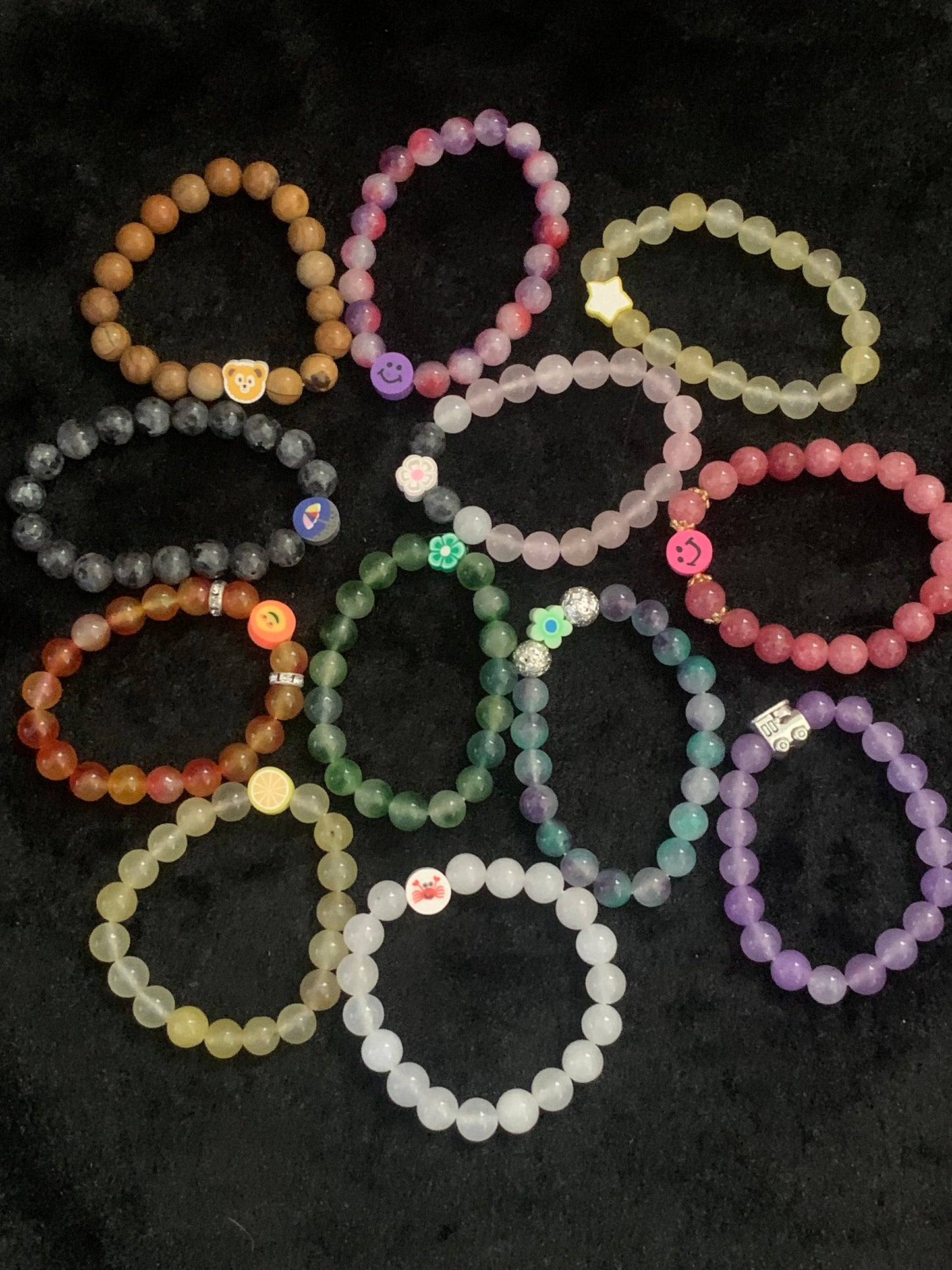 Colorful beaded bracelets arranged in a circular pattern on a dark surface