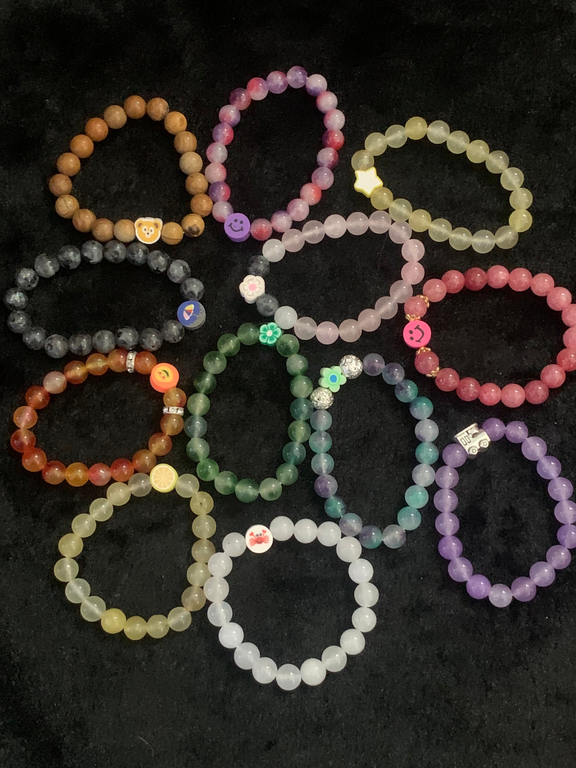 Colorful beaded bracelets arranged in a circular pattern on a dark surface