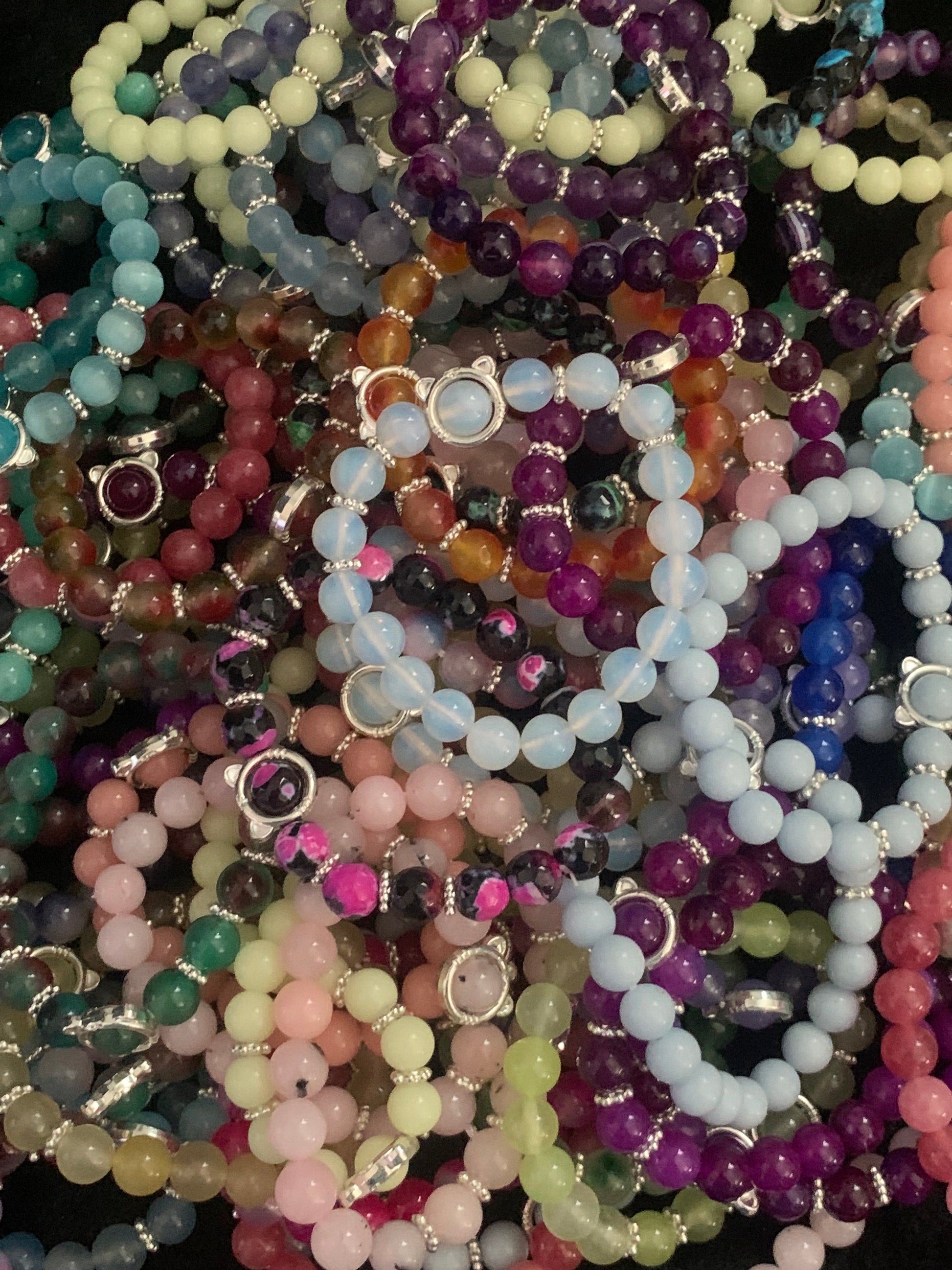 Stack of multicolored beaded bracelets on a dark background