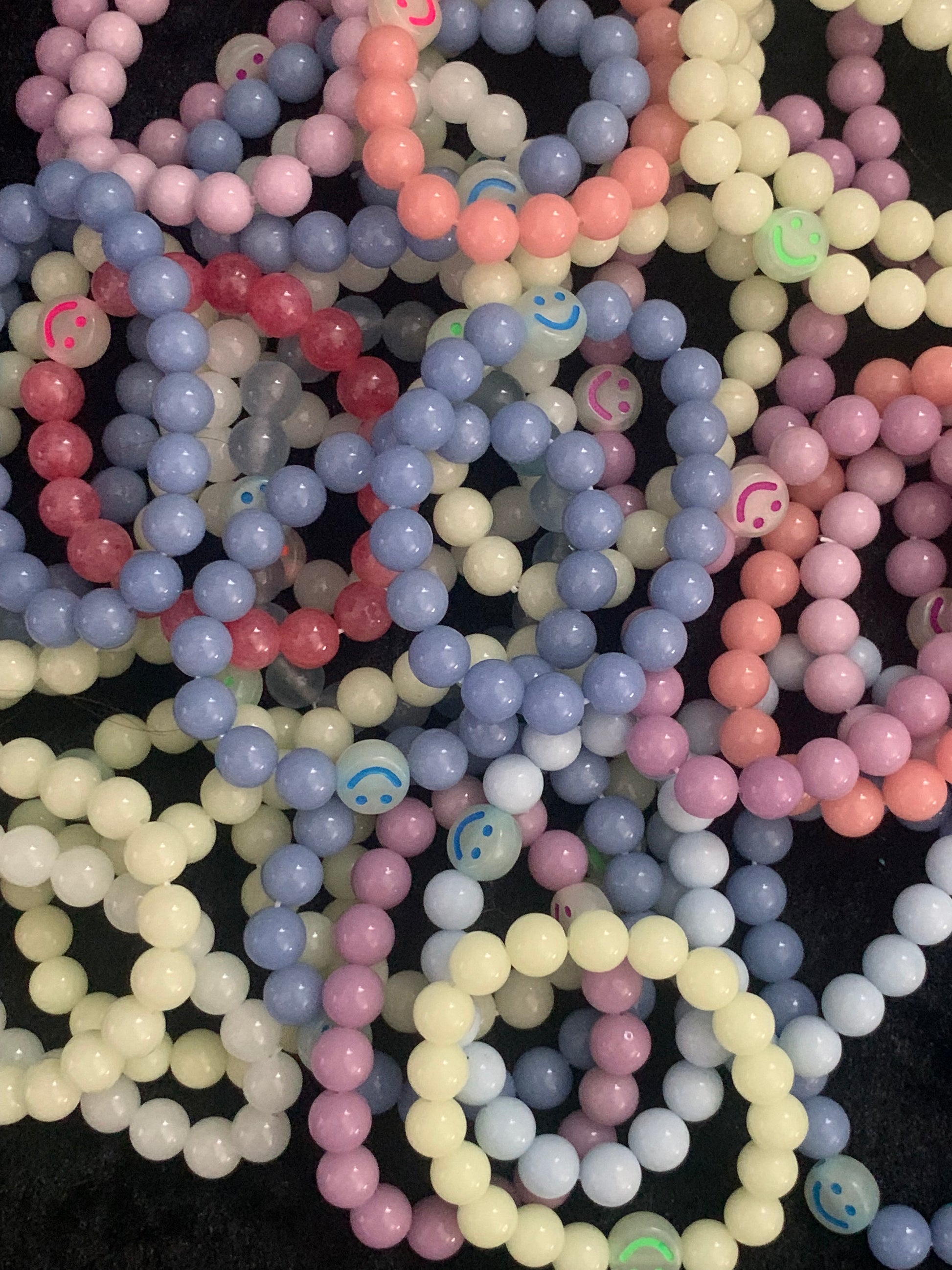 Pastel-colored bracelets with smiley face beads on a black background