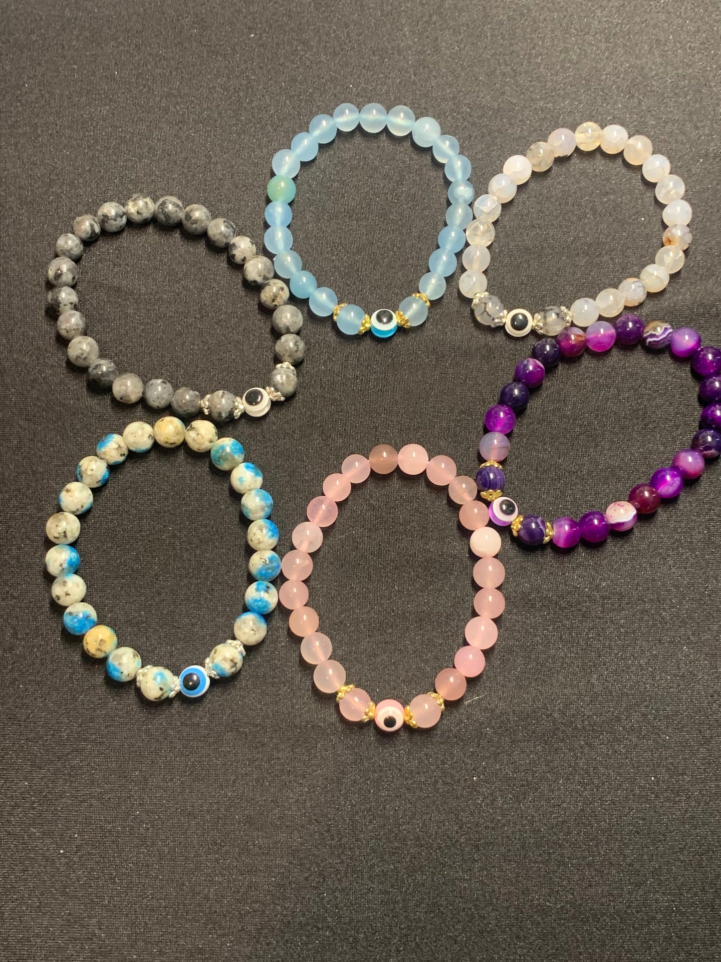 Set of six beaded bracelets in various colors on a dark surface