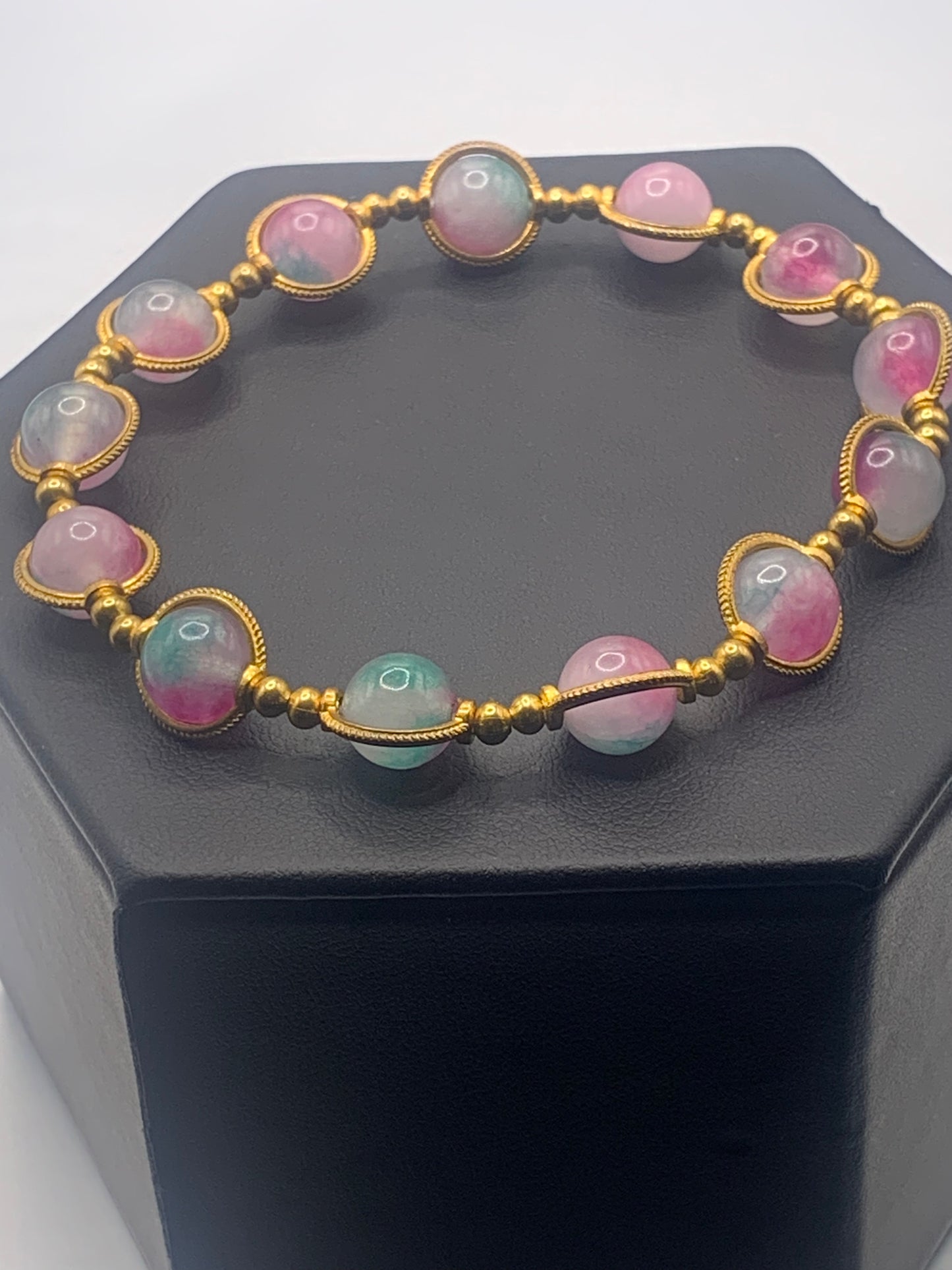 Bracelet with teal and pink chalcedony beads on a black stand