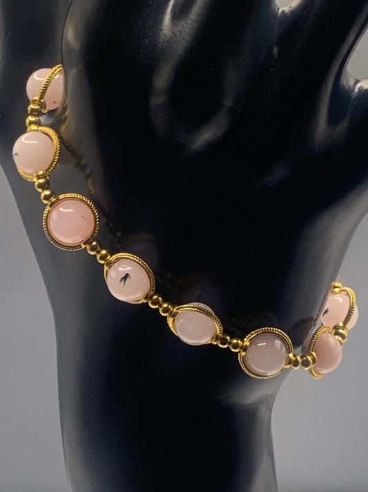 Bracelet with pink opal chalcedony beads and gold accents on a black mannequin.