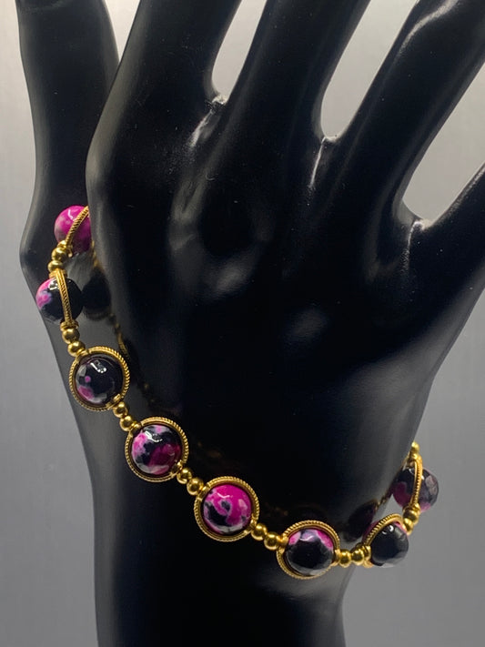 Bracelet with pink and black orca agate gemstones on a black mannequin hand