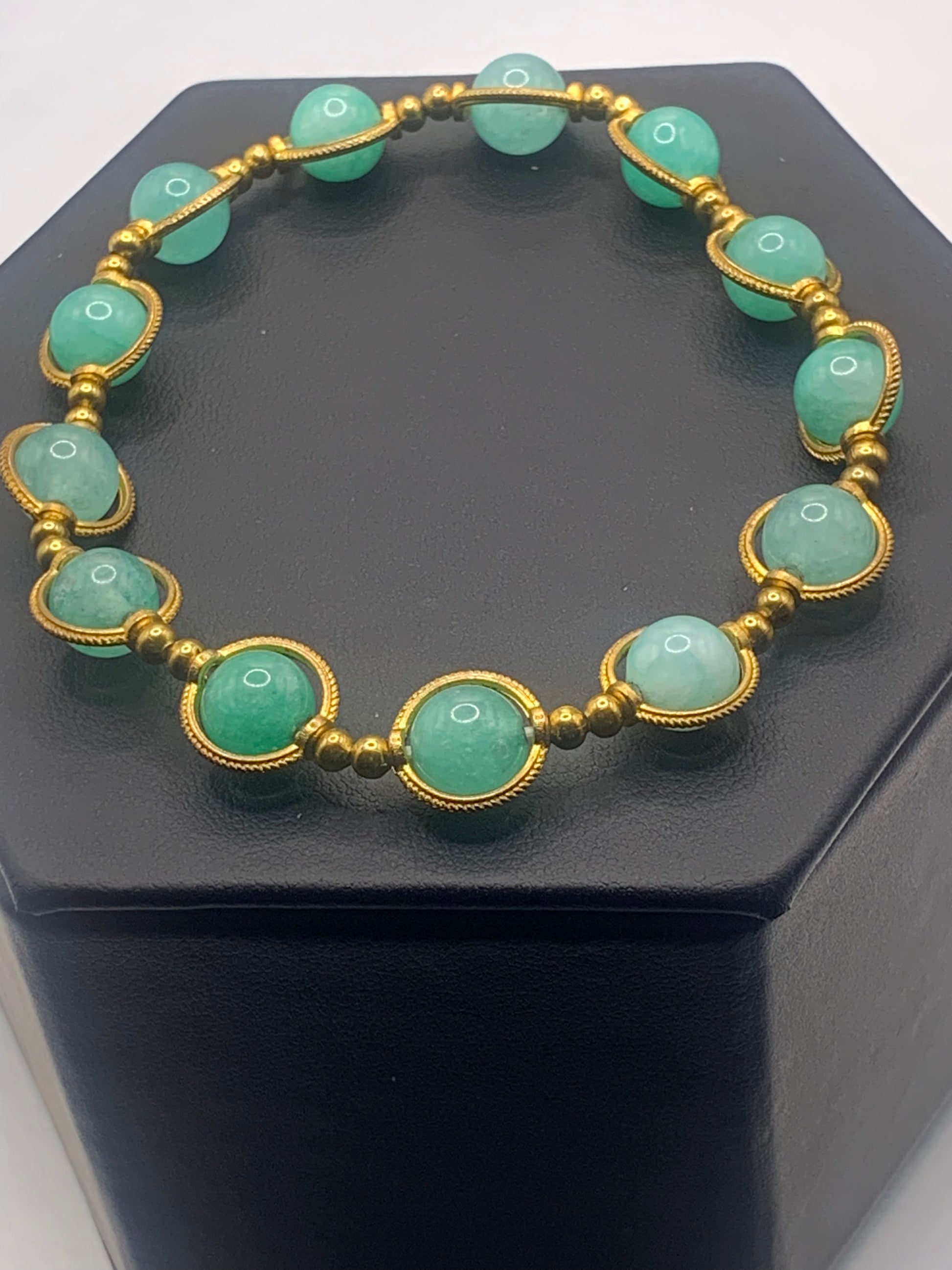 Bracelet with teal chalcedony beads and gold accents on a black box