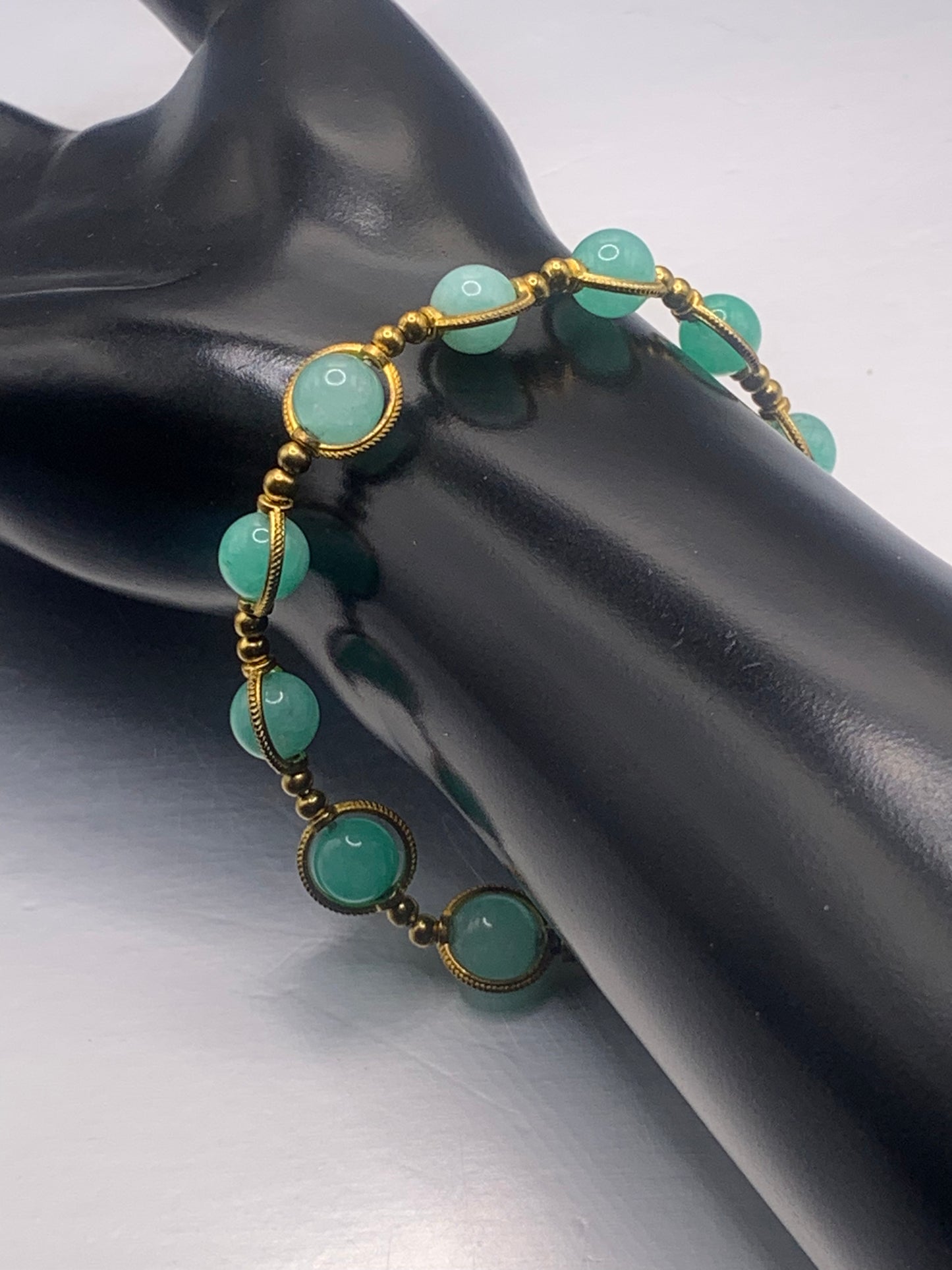 Bracelet with teal chalcedony beads and gold accents on a black mannequin hand