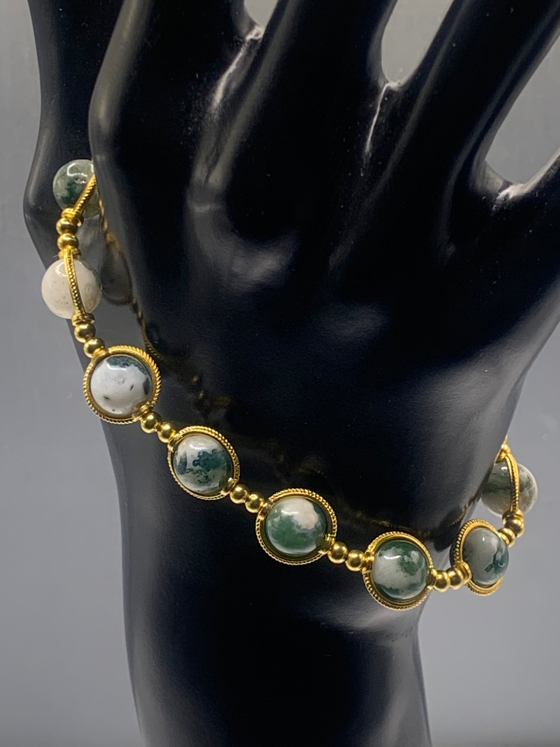 Bracelet with tree moss agate beads and gold accents on a black mannequin.