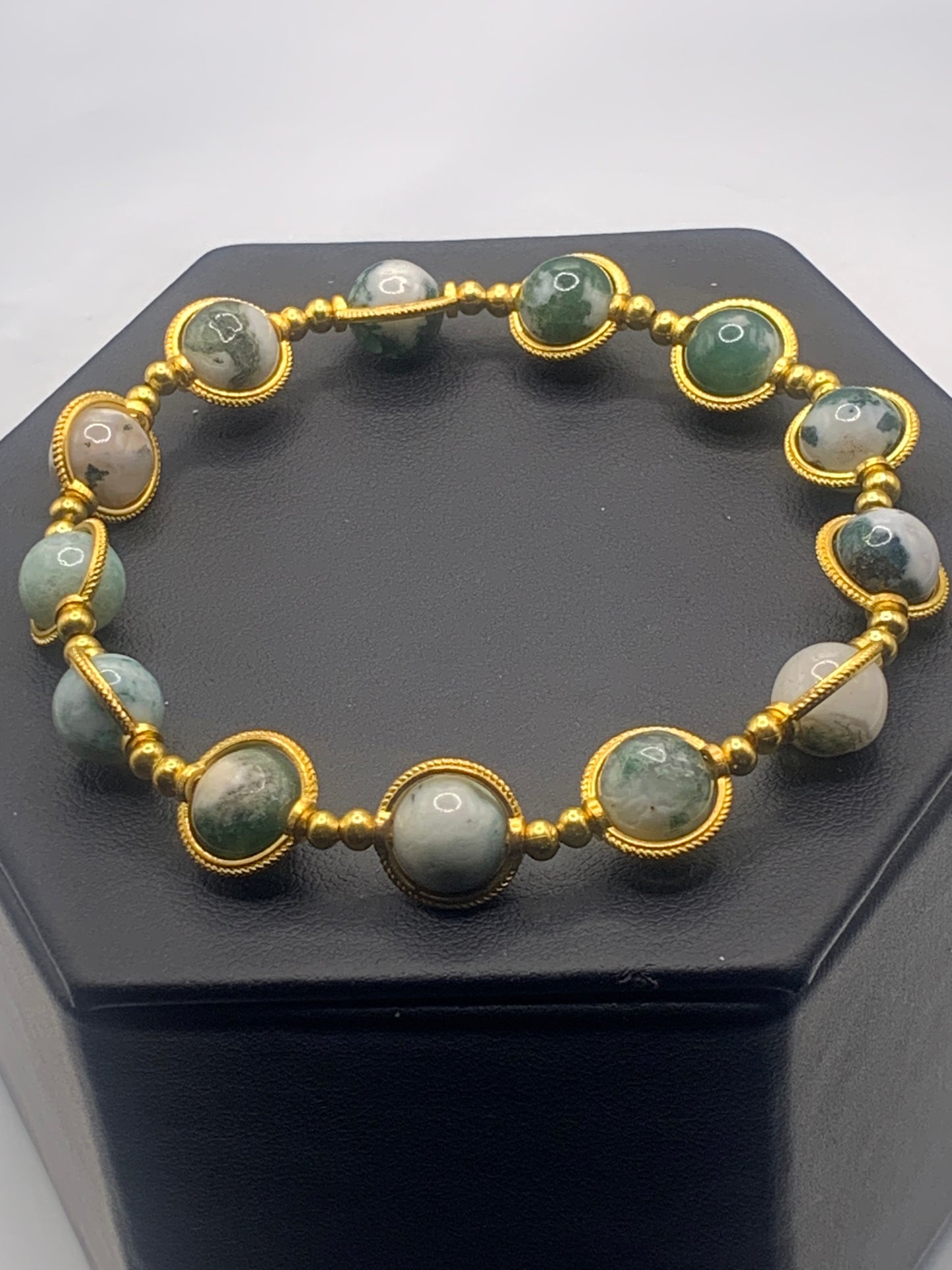Bracelet with tree moss agate beads and gold accents on a black stand