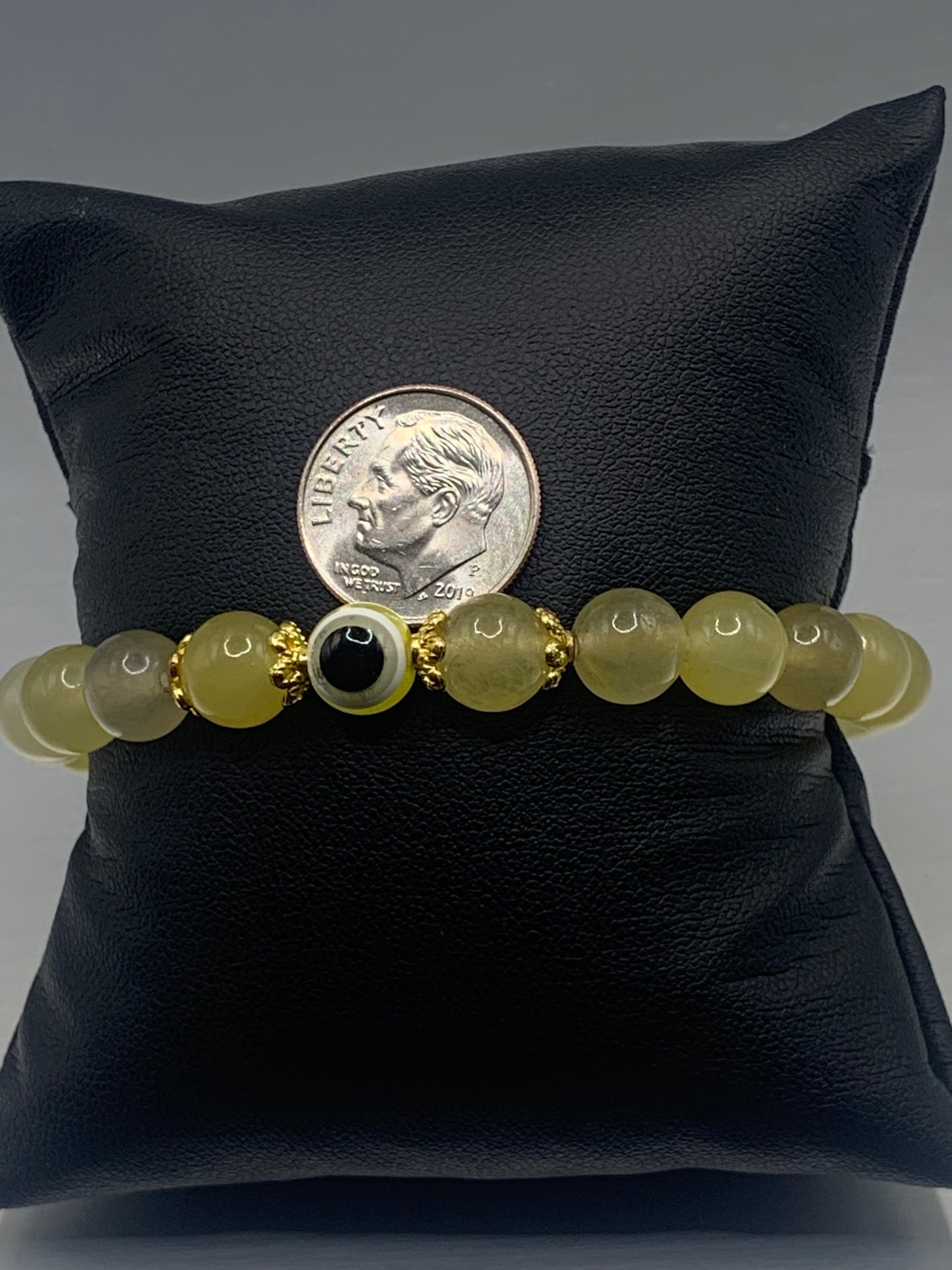 This bracelet features yellow agate beads and a colorful evil eye resin bead with gold flower caps. These are 8mm beads, made with elastic string to stretch onto the wrist and is approximately 17 cm or 6.7 inches.

These are natural semi-precious stones/crystals. Even if they are dyed, the base material is still natural and imperfections are common making them unique.