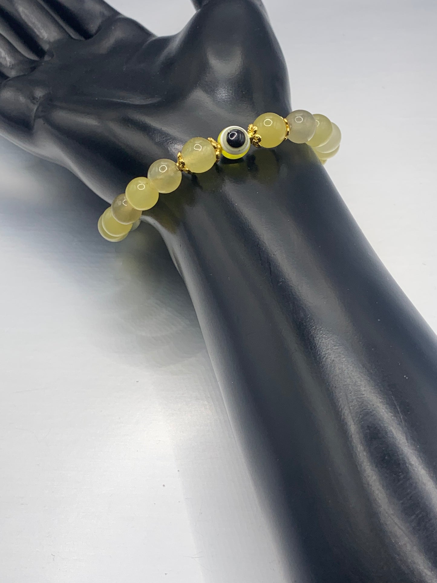 This bracelet features yellow agate beads and a colorful evil eye resin bead with gold flower caps. These are 8mm beads, made with elastic string to stretch onto the wrist and is approximately 17 cm or 6.7 inches.

These are natural semi-precious stones/crystals. Even if they are dyed, the base material is still natural and imperfections are common making them unique.