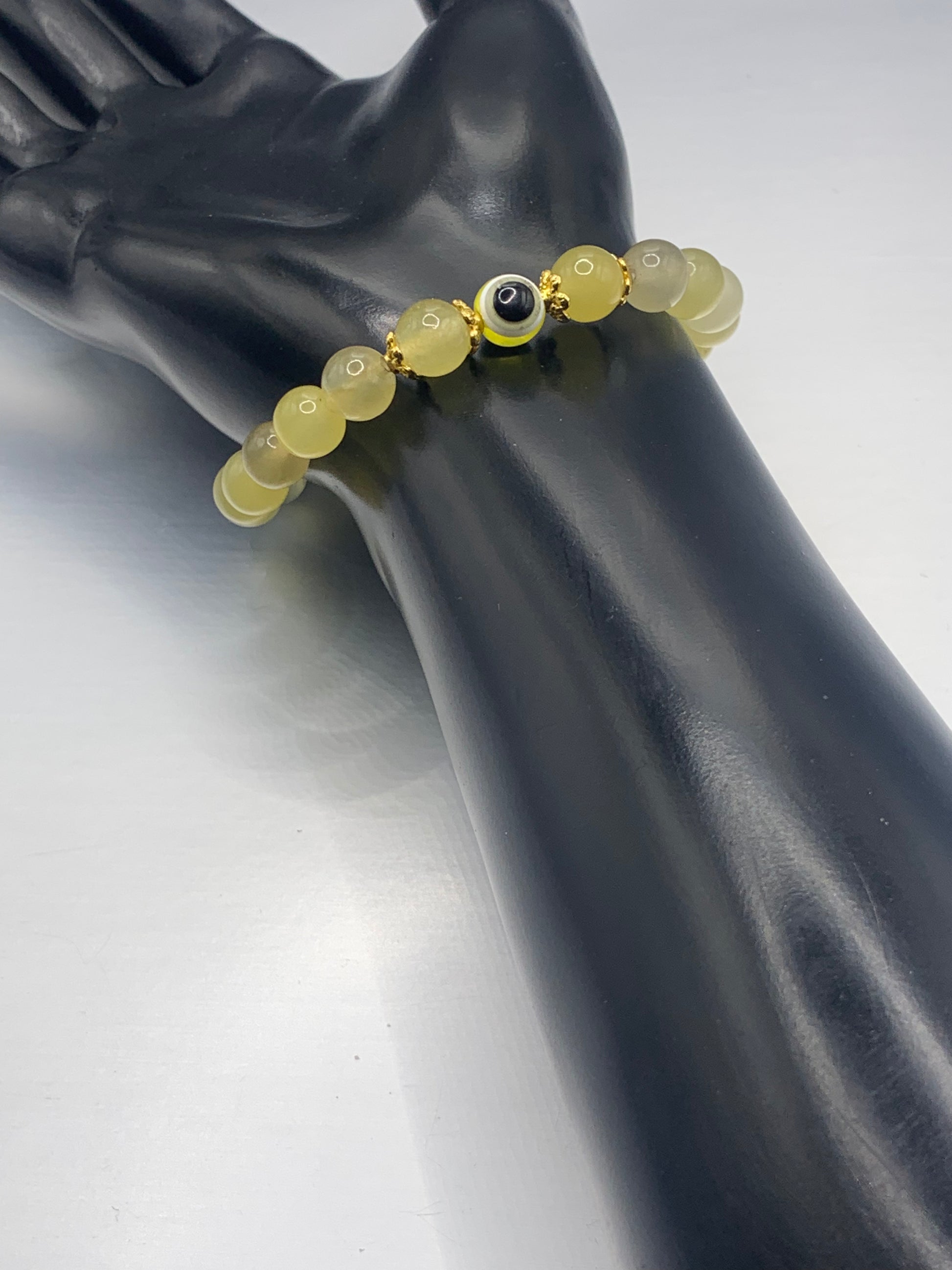 This bracelet features yellow agate beads and a colorful evil eye resin bead with gold flower caps. These are 8mm beads, made with elastic string to stretch onto the wrist and is approximately 17 cm or 6.7 inches.

These are natural semi-precious stones/crystals. Even if they are dyed, the base material is still natural and imperfections are common making them unique.