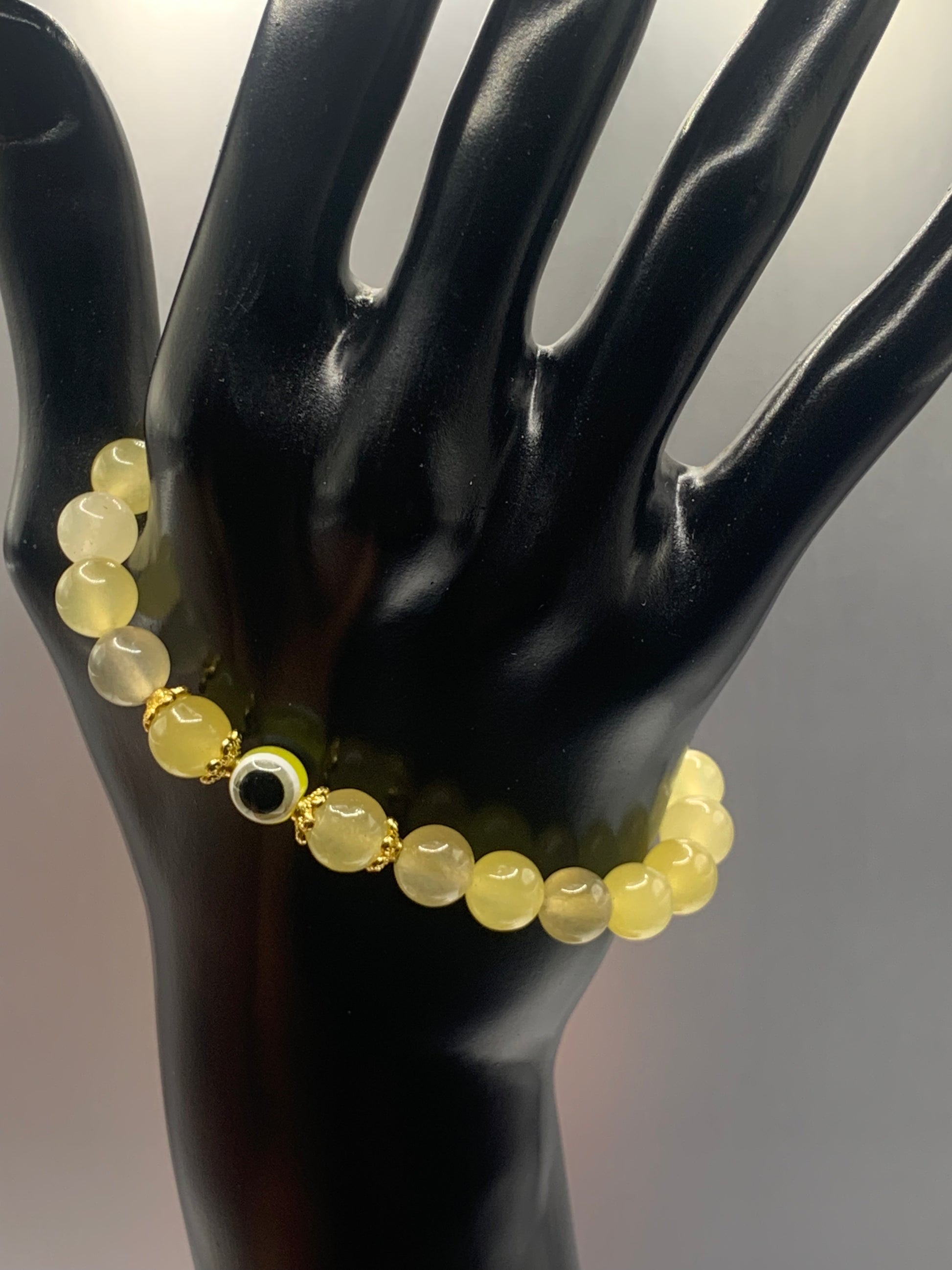 This bracelet features yellow agate beads and a colorful evil eye resin bead with gold flower caps. These are 8mm beads, made with elastic string to stretch onto the wrist and is approximately 17 cm or 6.7 inches.

These are natural semi-precious stones/crystals. Even if they are dyed, the base material is still natural and imperfections are common making them unique.
