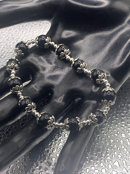This bracelet contains black obsidian beads that are surrounded by bead caps and spacer beads