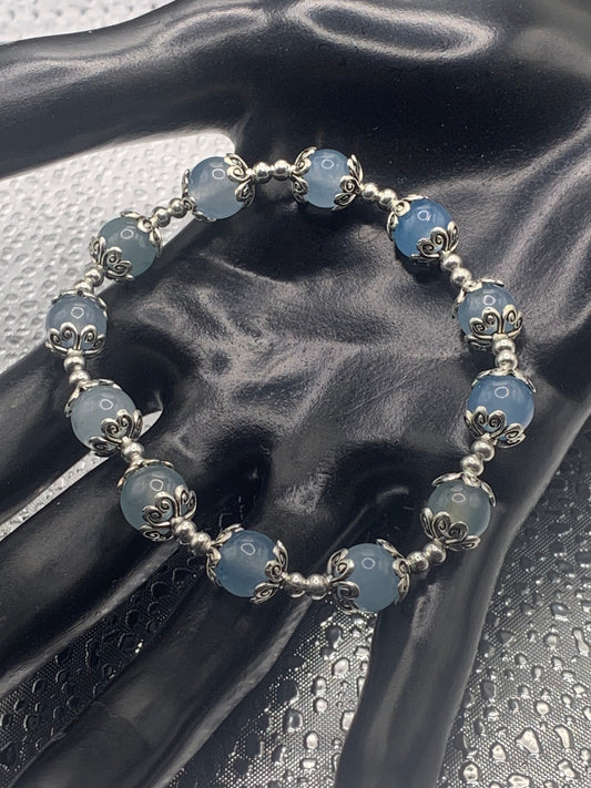 This bracelet contains blue agate beads that are surrounded by bead caps and spacer beads