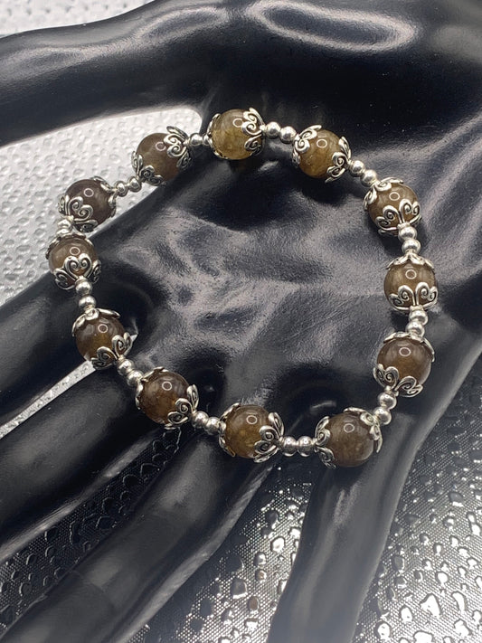 This bracelet contains brown chalcedony beads that are surrounded by bead caps and spacer beads