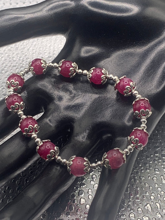 This bracelet contains dark pink chalcedony beads that are surrounded by bead caps and spacer beads