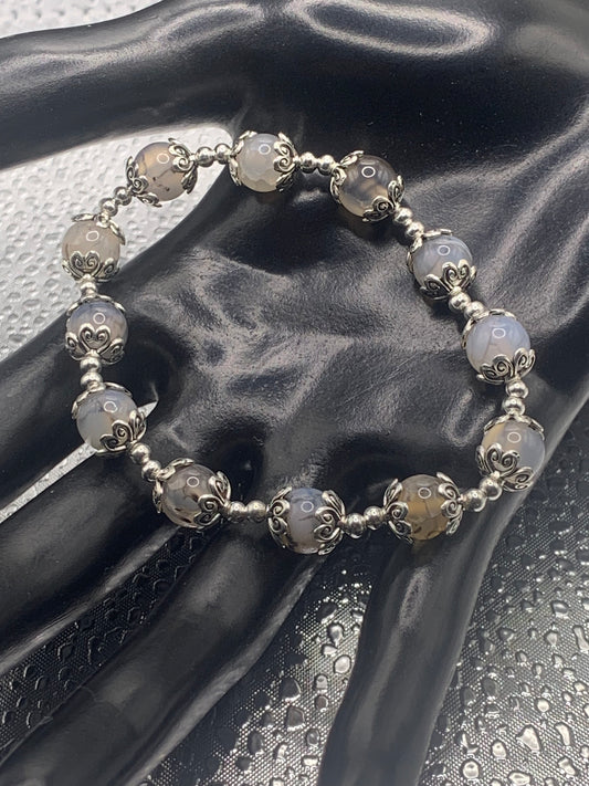 This bracelet contains dragon vein agate beads that are surrounded by bead caps and spacer beads