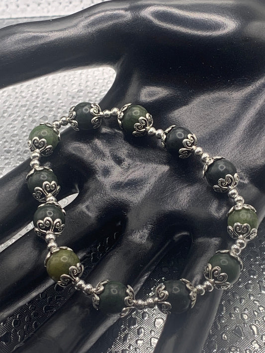 This bracelet contains green jade beads that are surrounded by bead caps and spacer beads