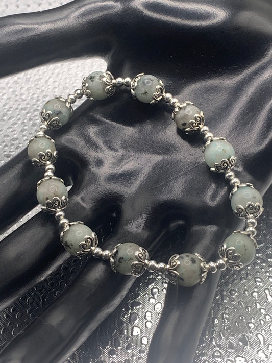 This bracelet contains kiwi jasper beads that are surrounded by bead caps and spacer beads