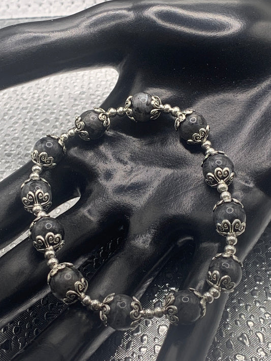 This bracelet contains larvikite beads that are surrounded by bead caps and spacer beads.