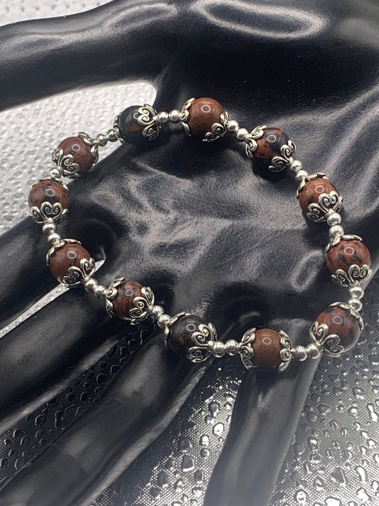 This bracelet contains mahogany jasper beads that are surrounded by bead caps and spacer beads