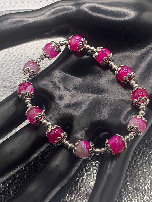 This bracelet contains pink lace agate beads that are surrounded by bead caps and spacer beads