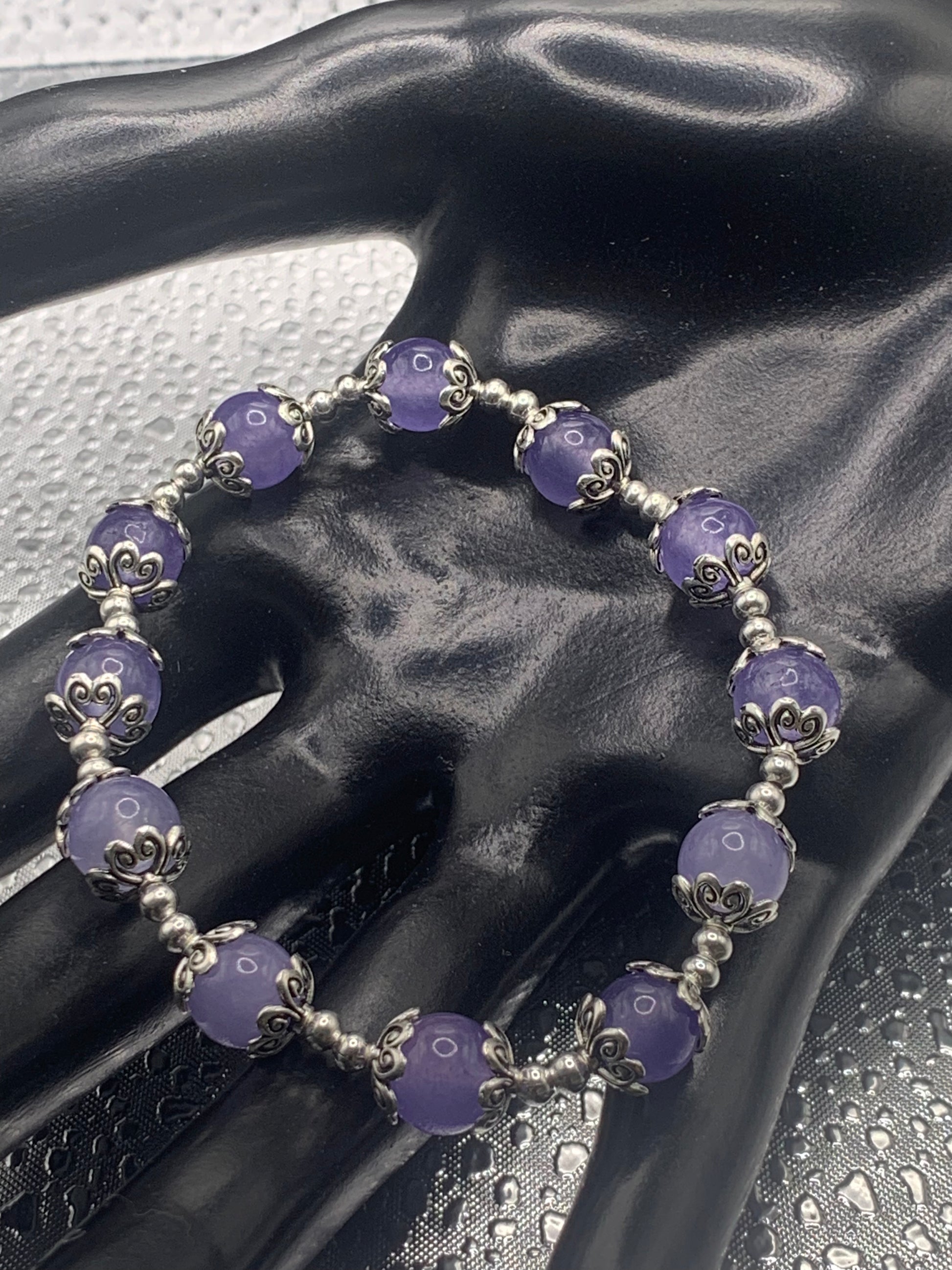 This bracelet contains purple agate beads that are surrounded by bead caps and spacer beads