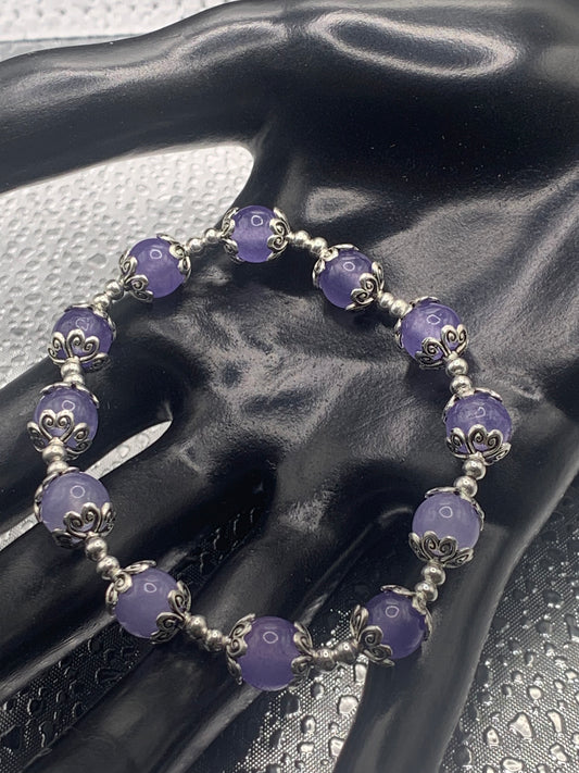 This bracelet contains purple agate beads that are surrounded by bead caps and spacer beads