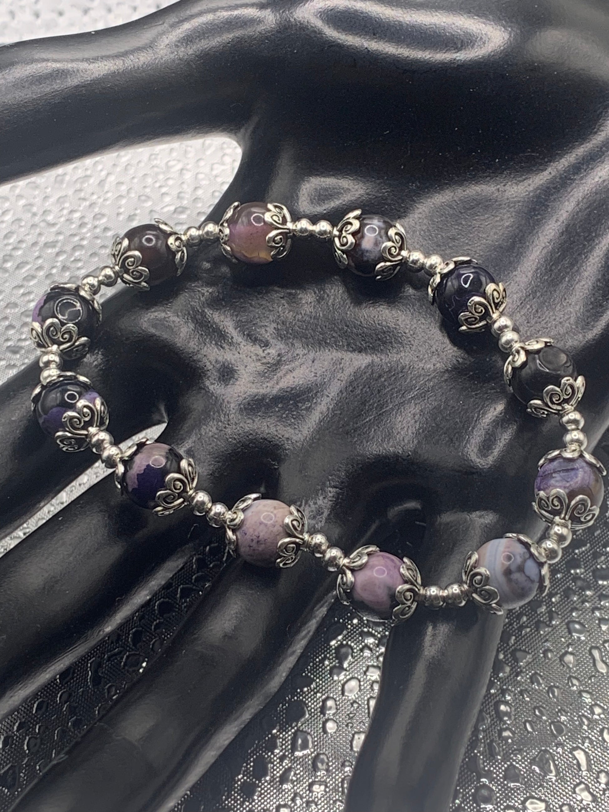 This bracelet contains purple orca agate beads that are surrounded by bead caps and spacer beads