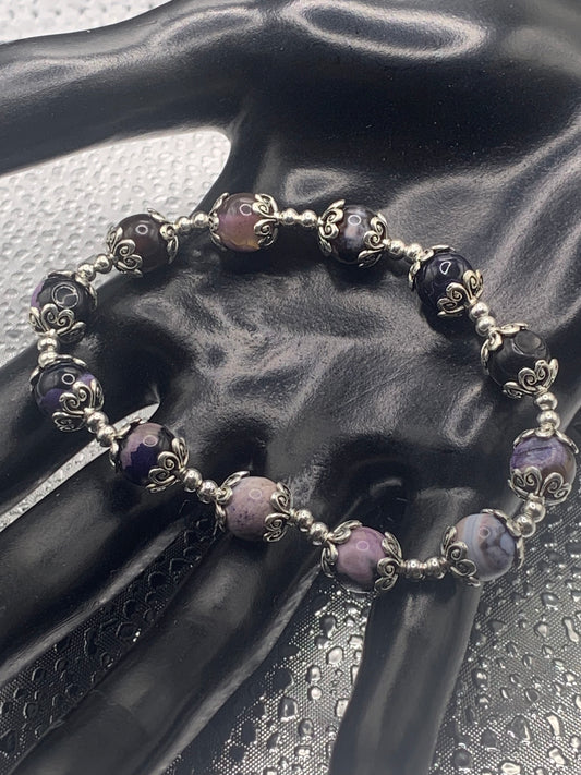 This bracelet contains purple orca agate beads that are surrounded by bead caps and spacer beads