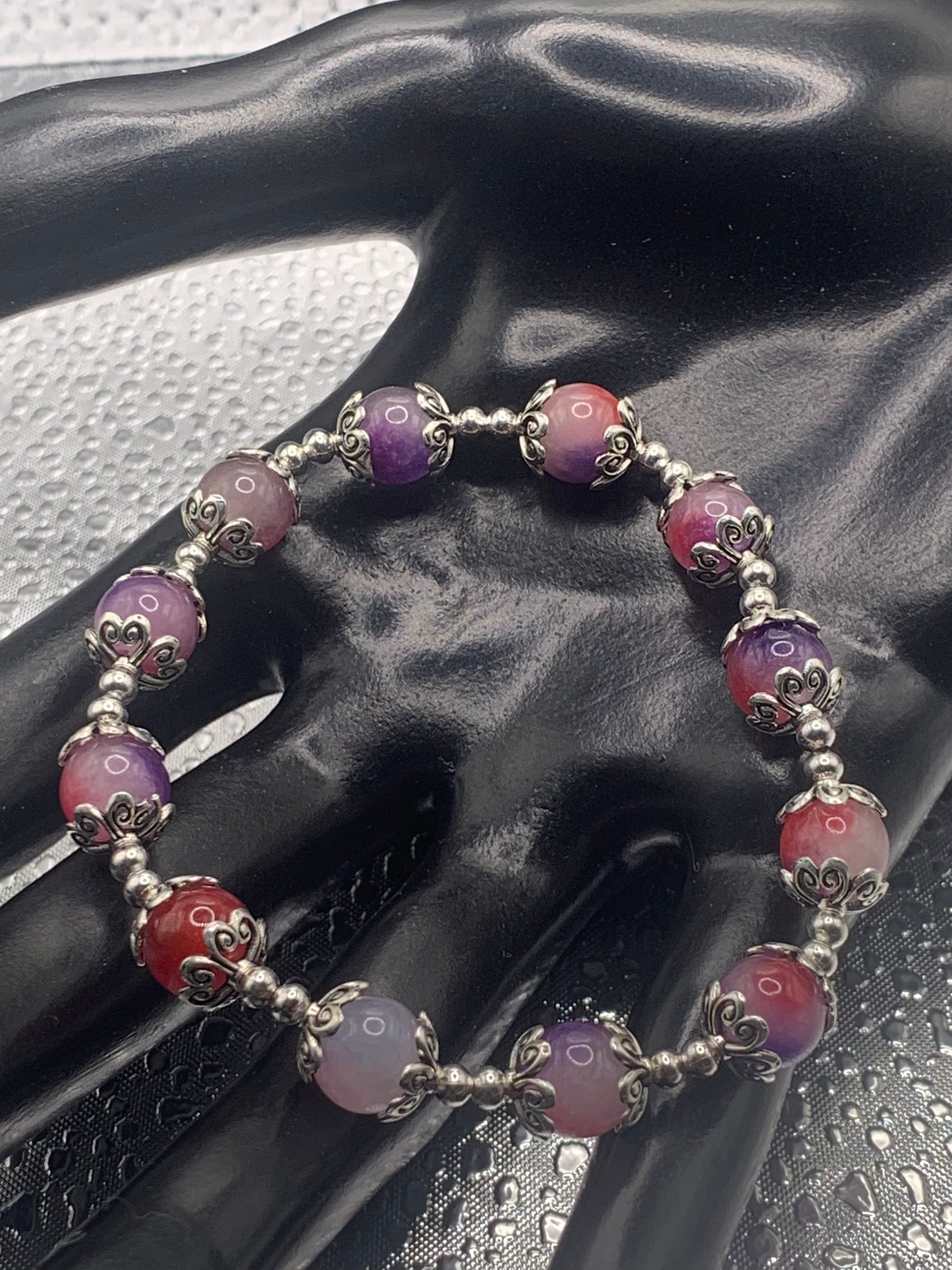 This bracelet contains purple pink agate beads that are surrounded by bead caps and spacer beads