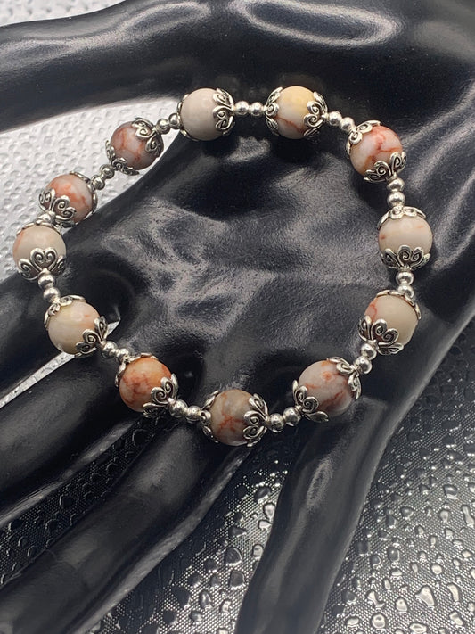 This bracelet contains red vein jasper beads that are surrounded by bead caps and spacer beads